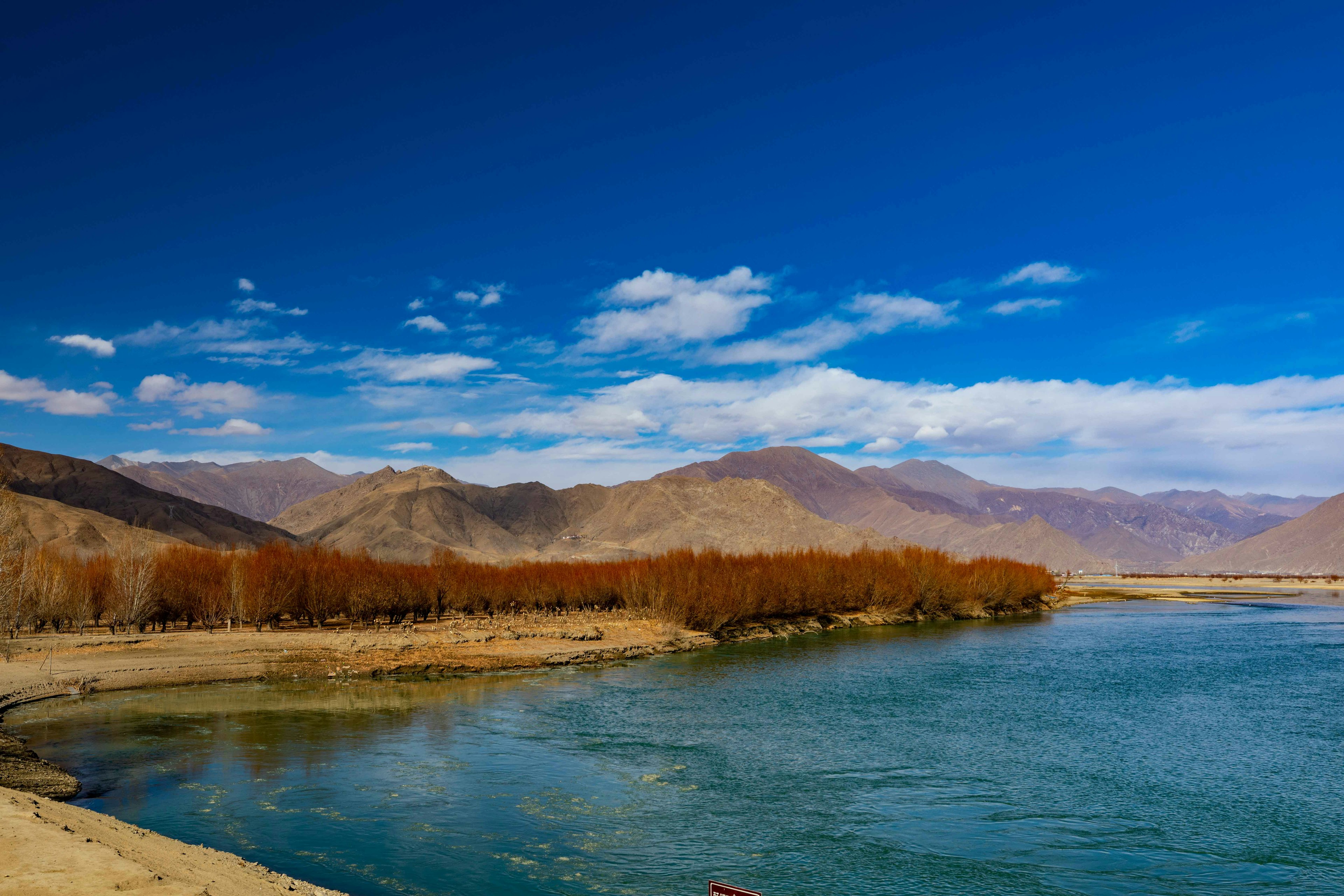 Scenic view of a river with mountains and a clear blue sky