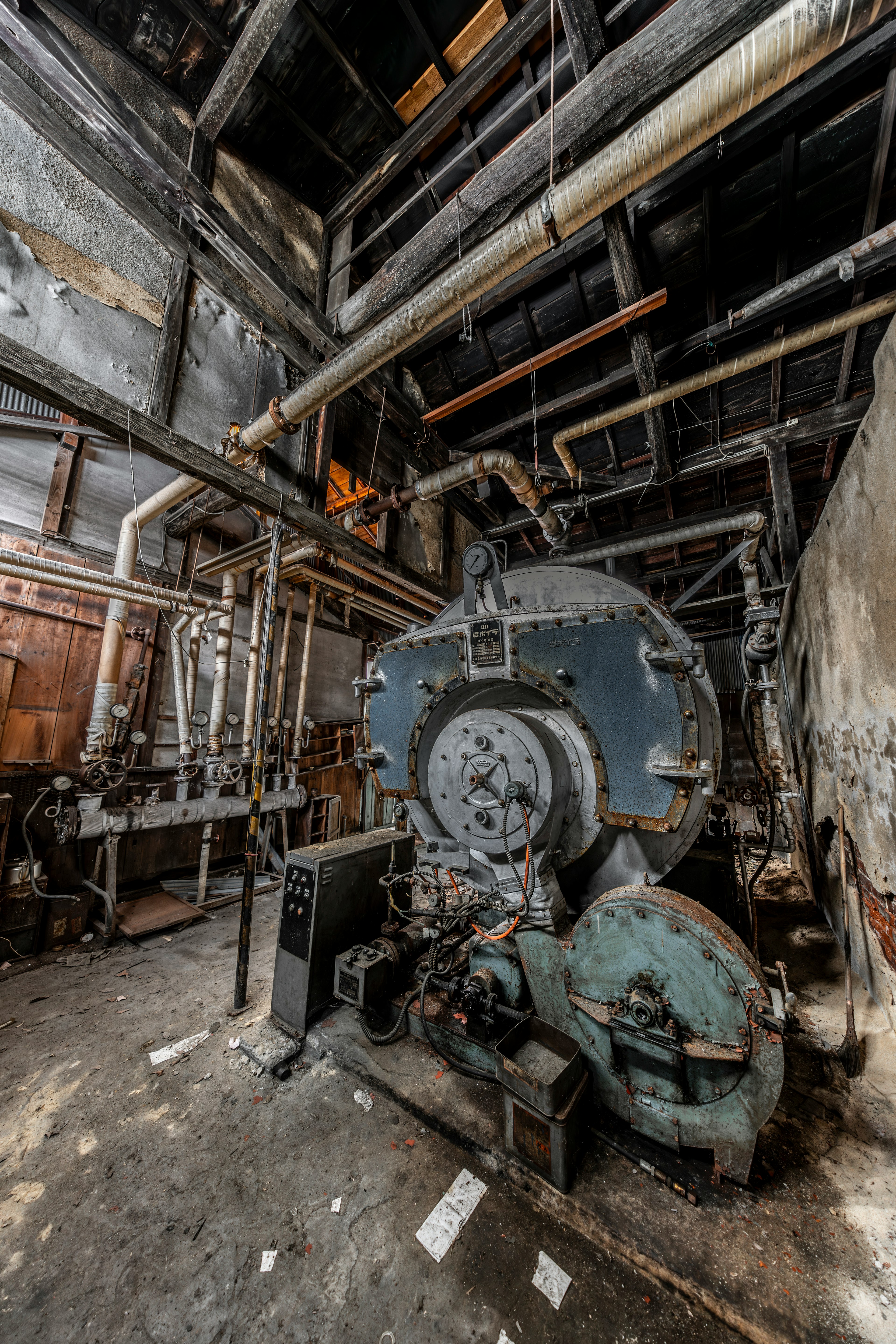 Interior of an old factory featuring a large boiler and intricate piping