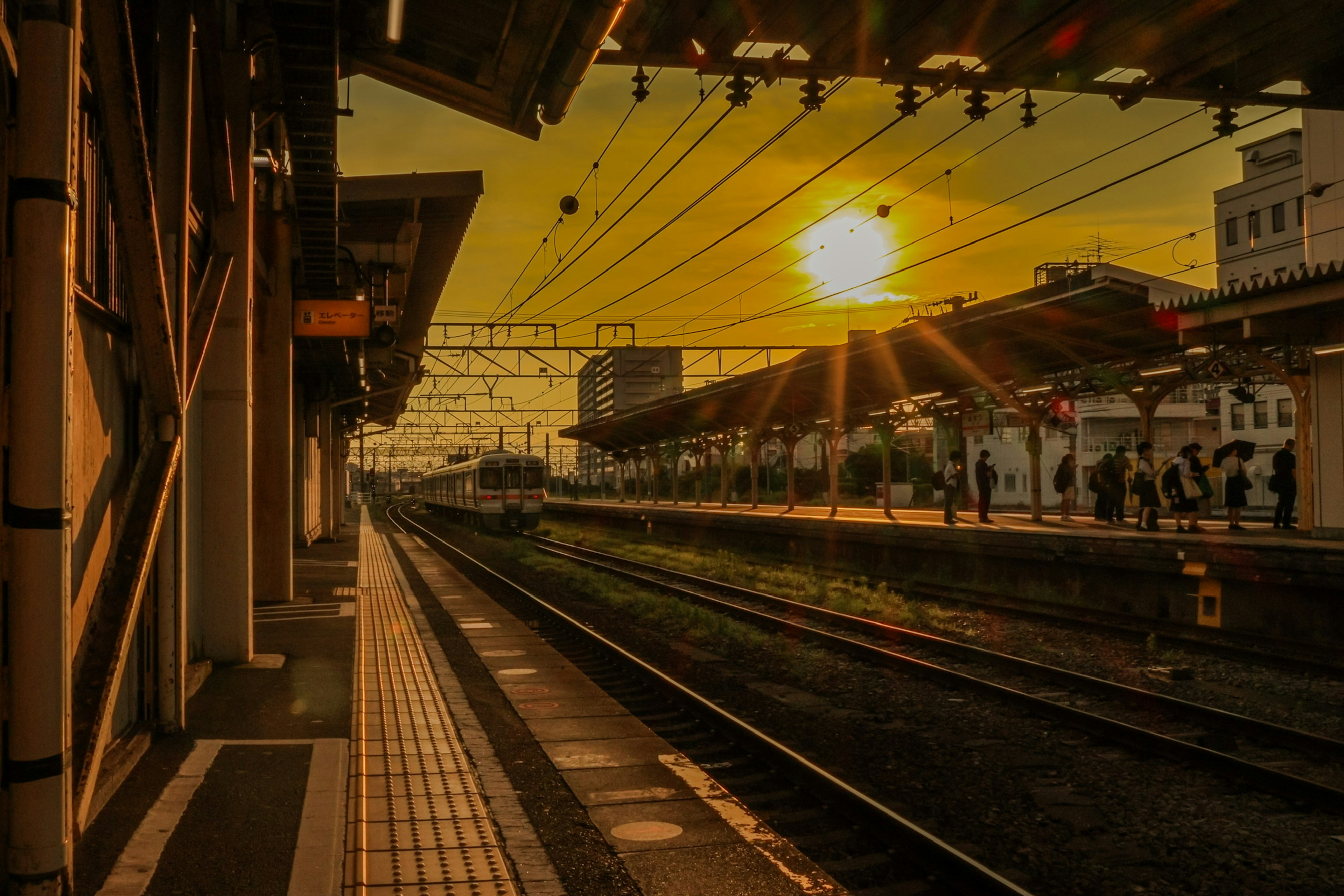 Plataforma de estación con atardecer y vías de tren