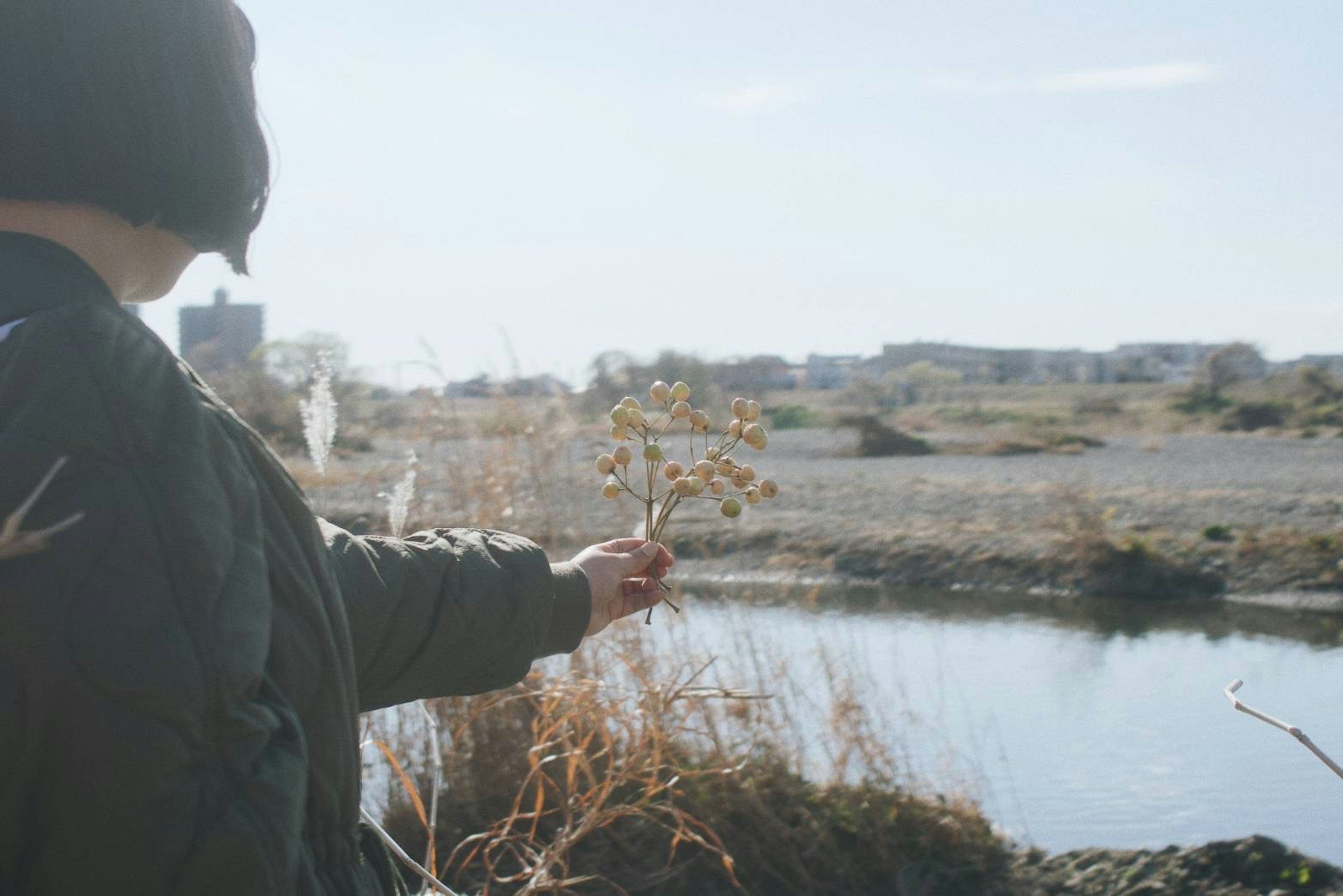 Una persona sosteniendo una ramita cerca de un río en un paisaje natural