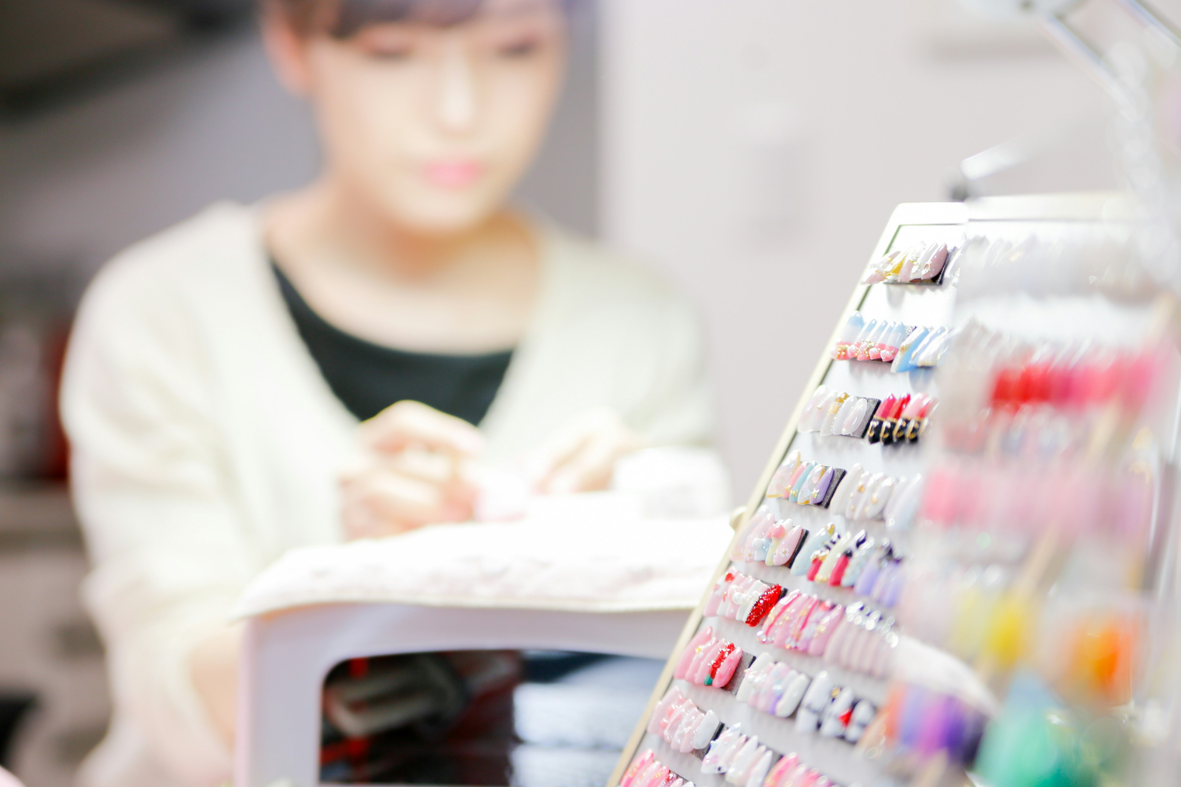 A woman applying nail art with colorful nail polish bottles in the foreground