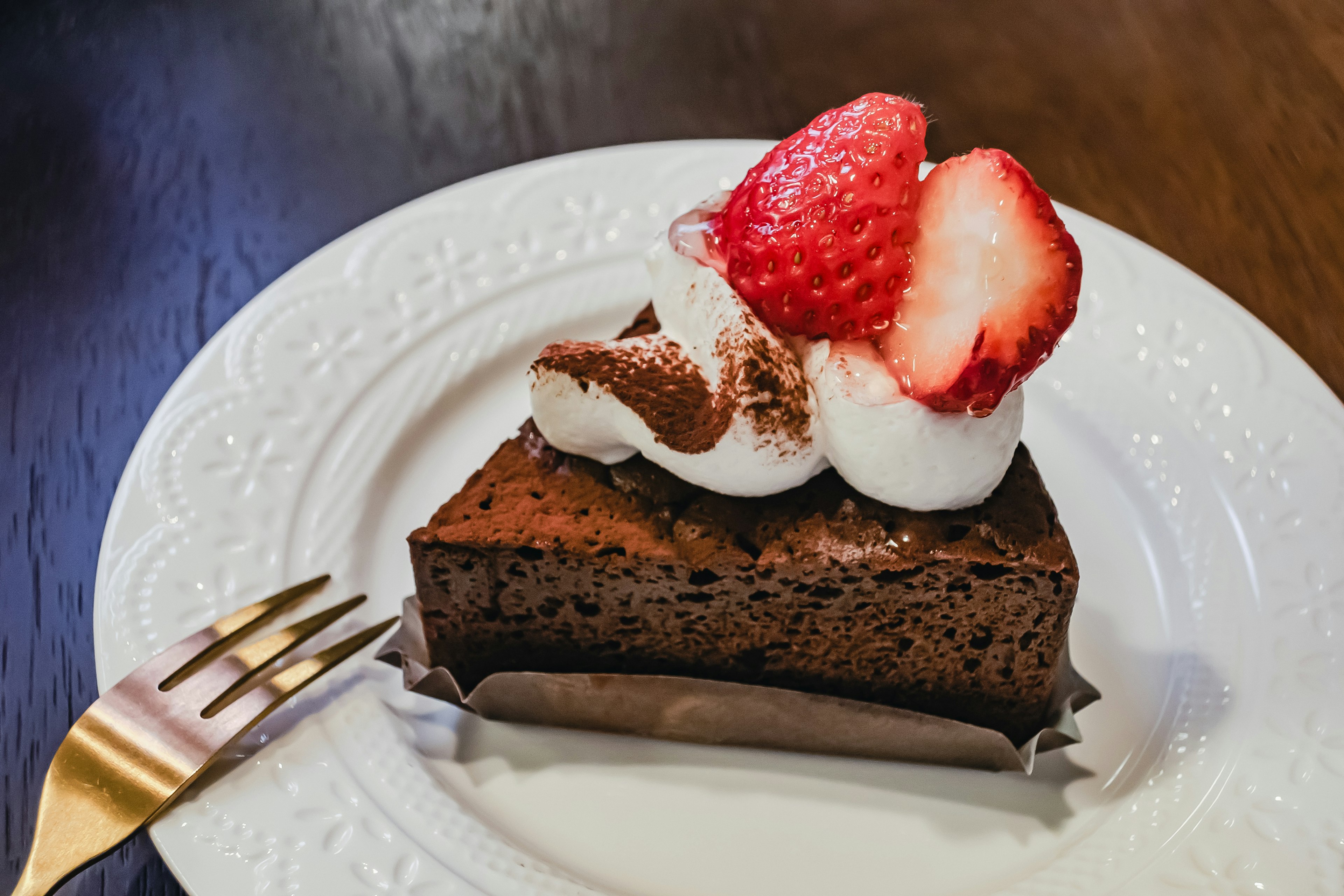 Schokoladenkuchen mit Sahne und Erdbeeren garniert