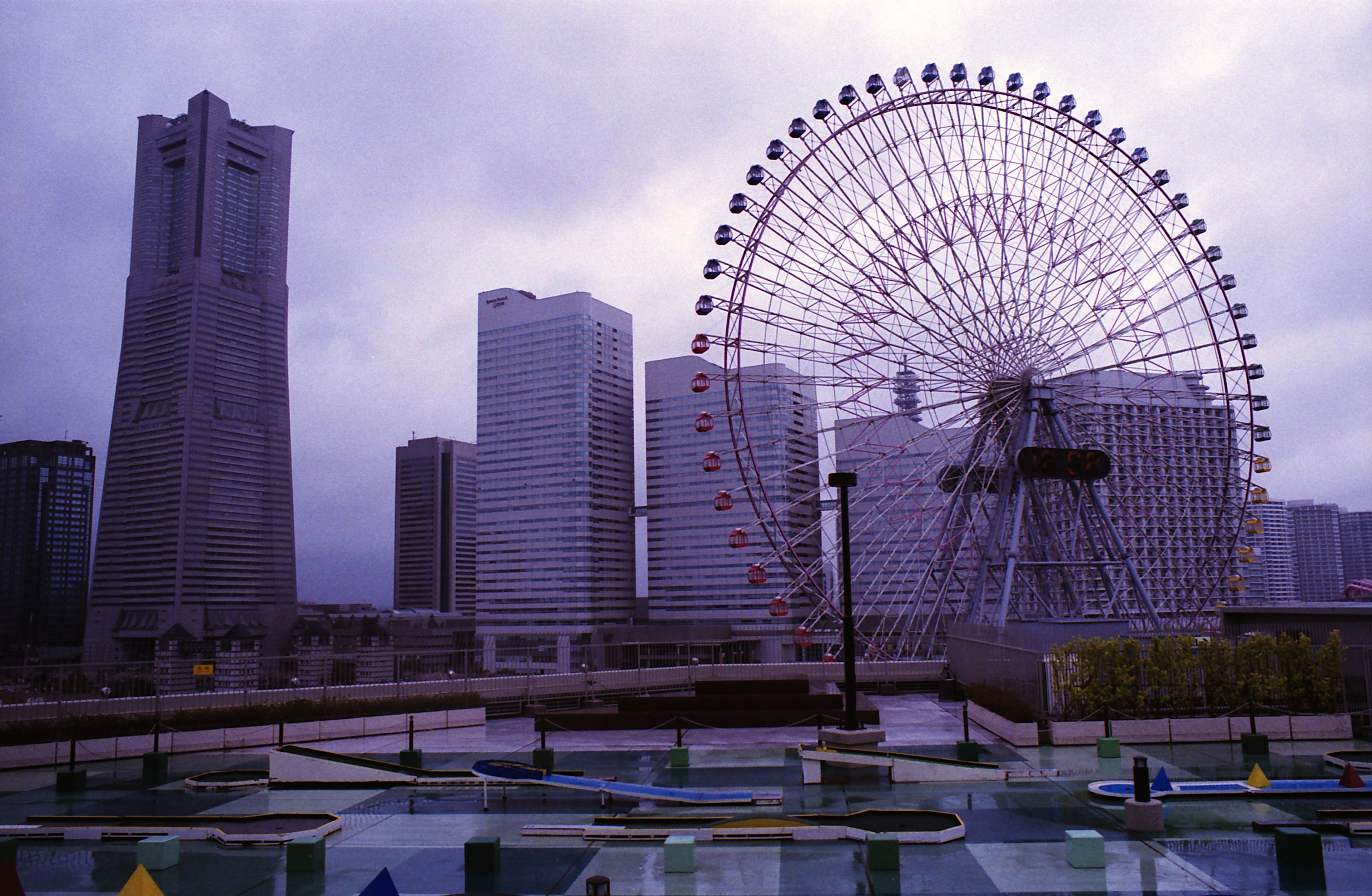 Skyline di Yokohama con una ruota panoramica e grattacieli sotto un cielo nuvoloso