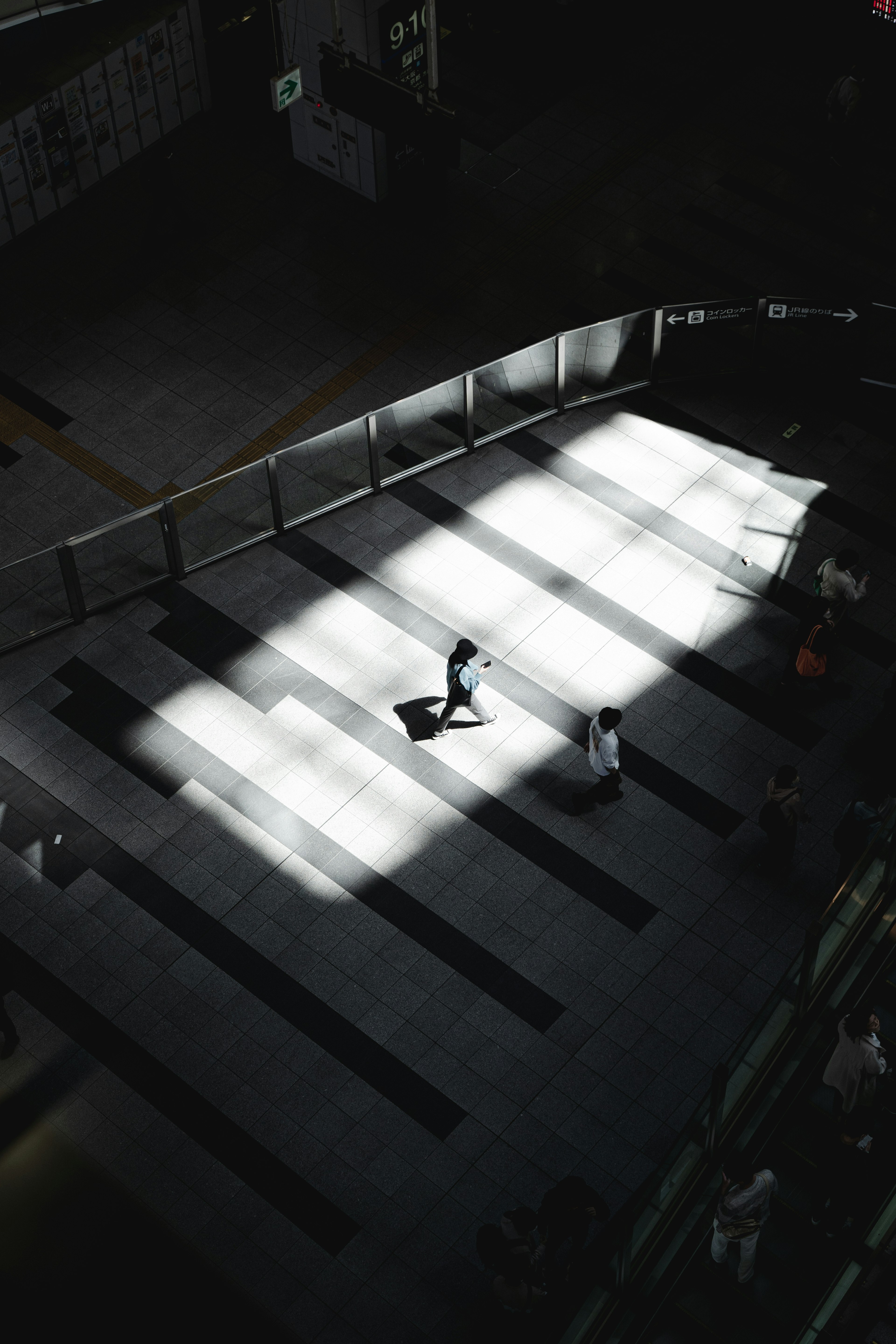 Escena urbana con personas caminando en luz y sombra contrastantes