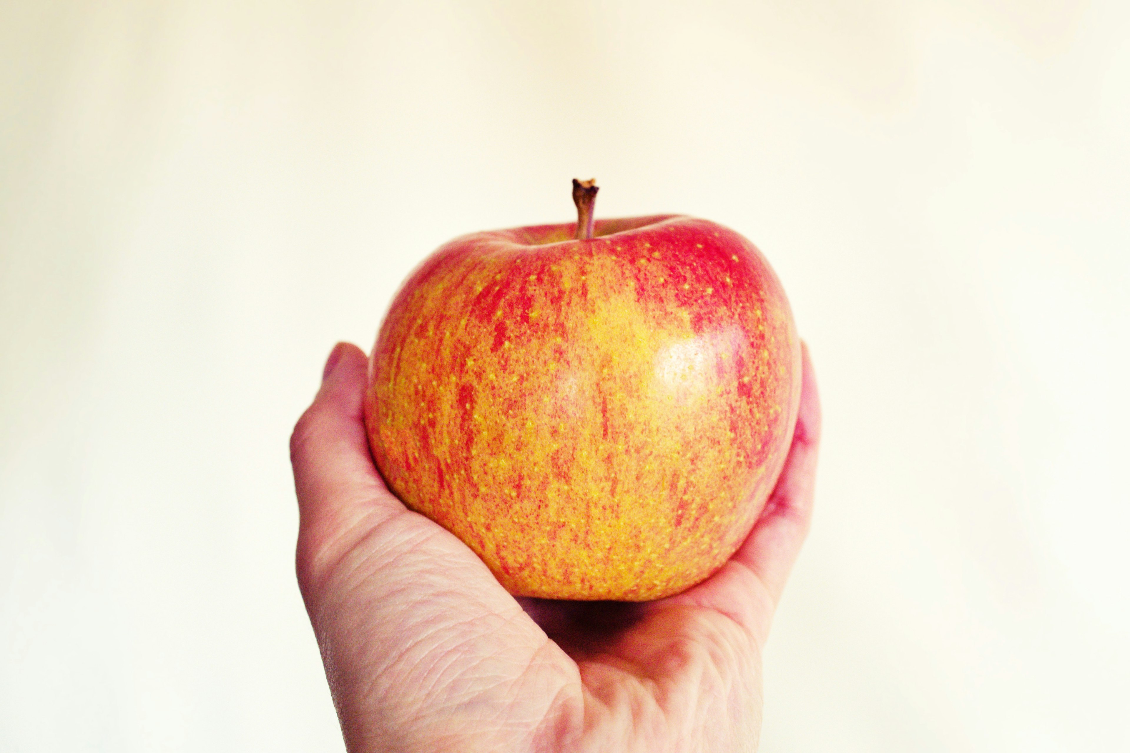 A hand holding a red apple