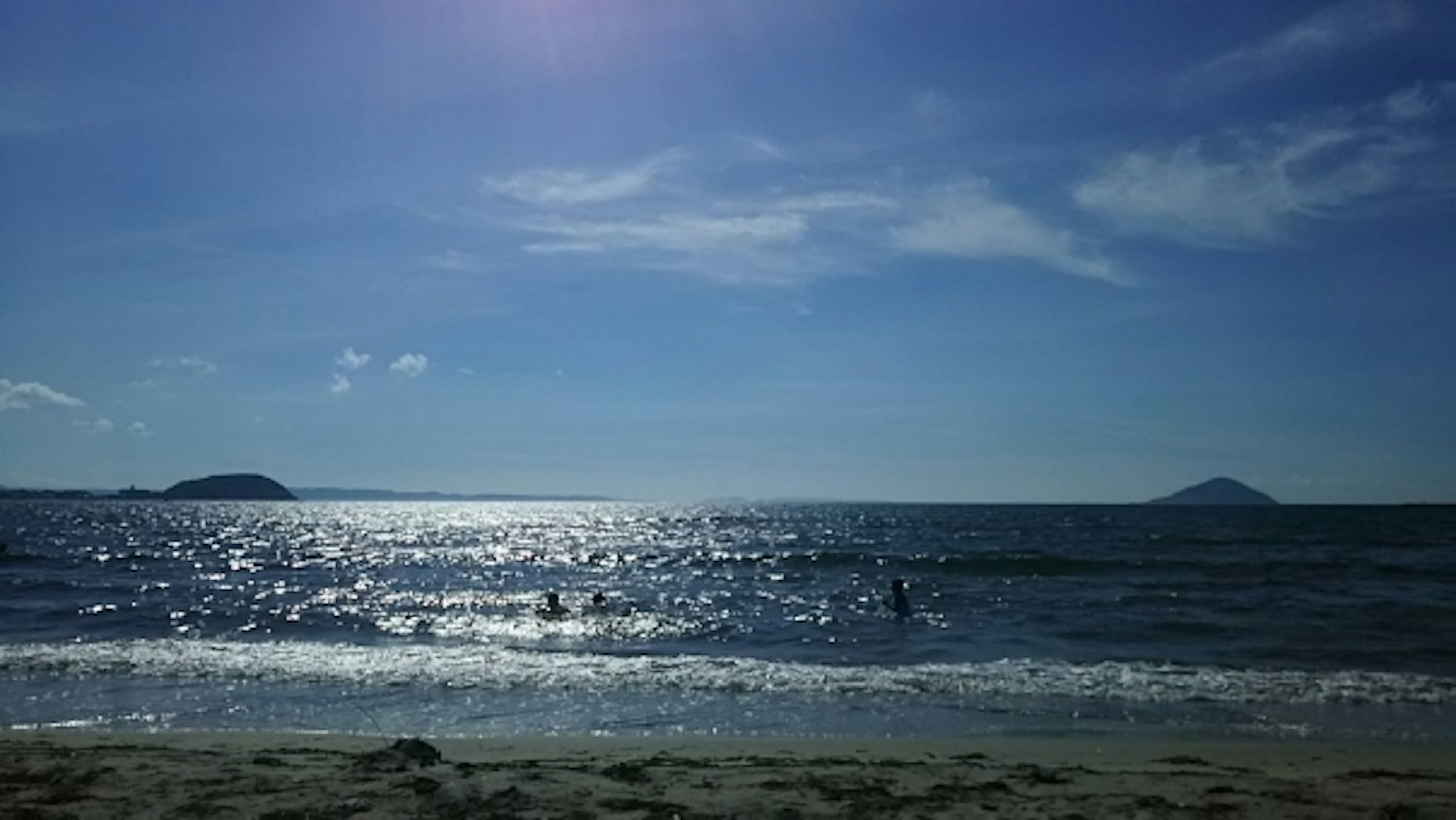 Malerei eines blauen Meeres und Himmels mit schimmernden Wellen und Sandstrand