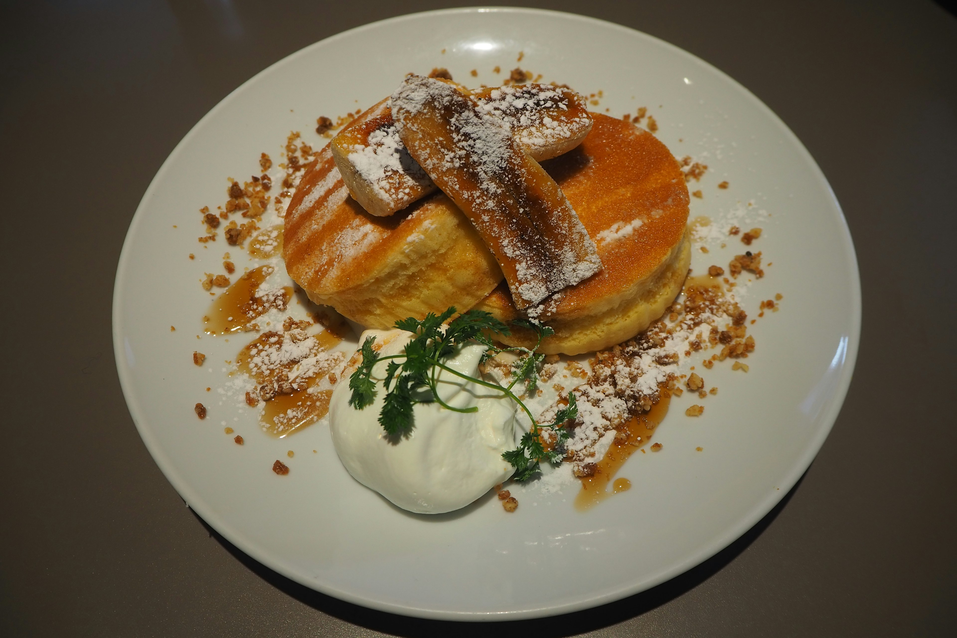 Panqueques esponjosos cubiertos de azúcar en polvo y salsa de frutas acompañados de crema batida