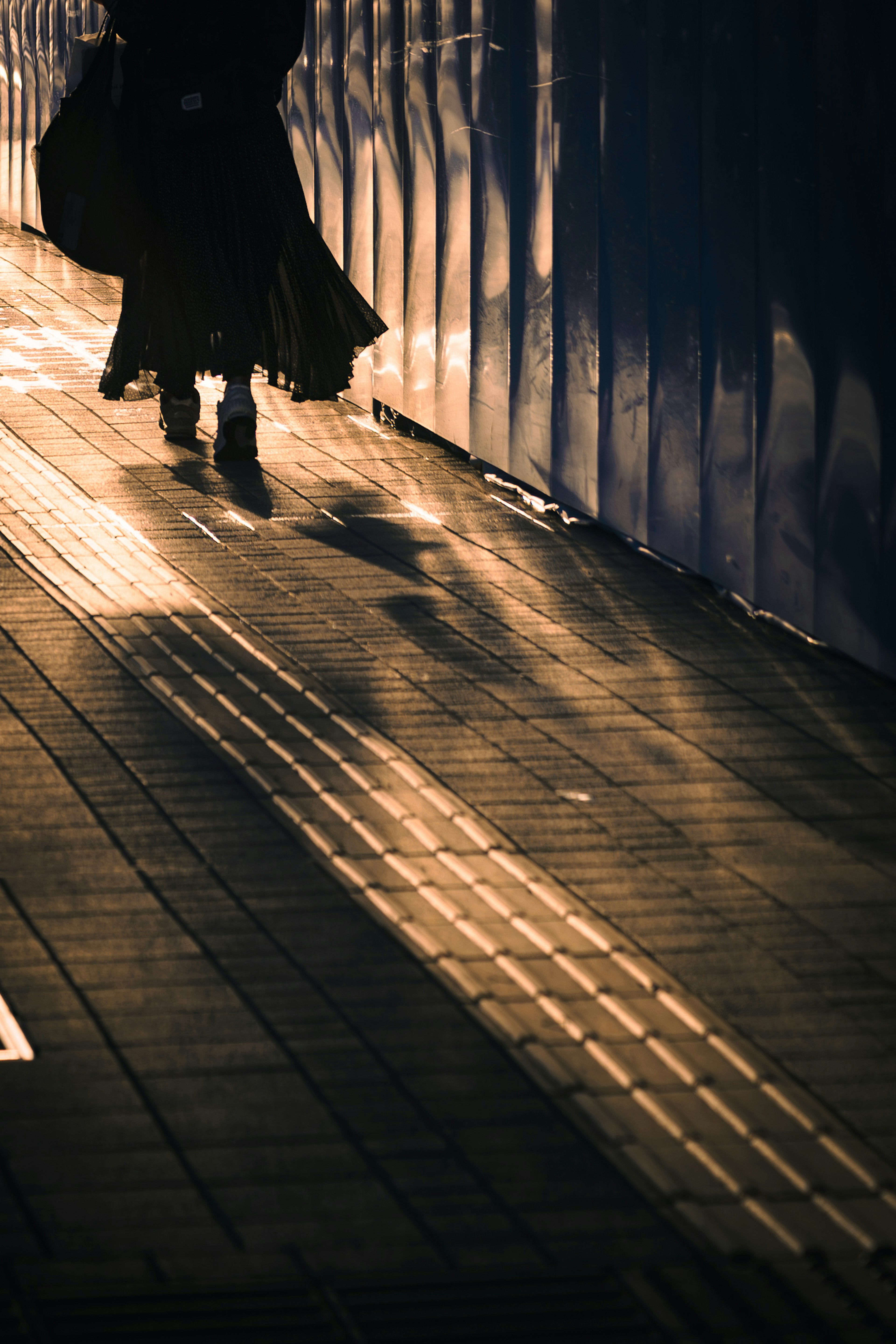 Silhouette of a person walking on a sunset street with striking shadows