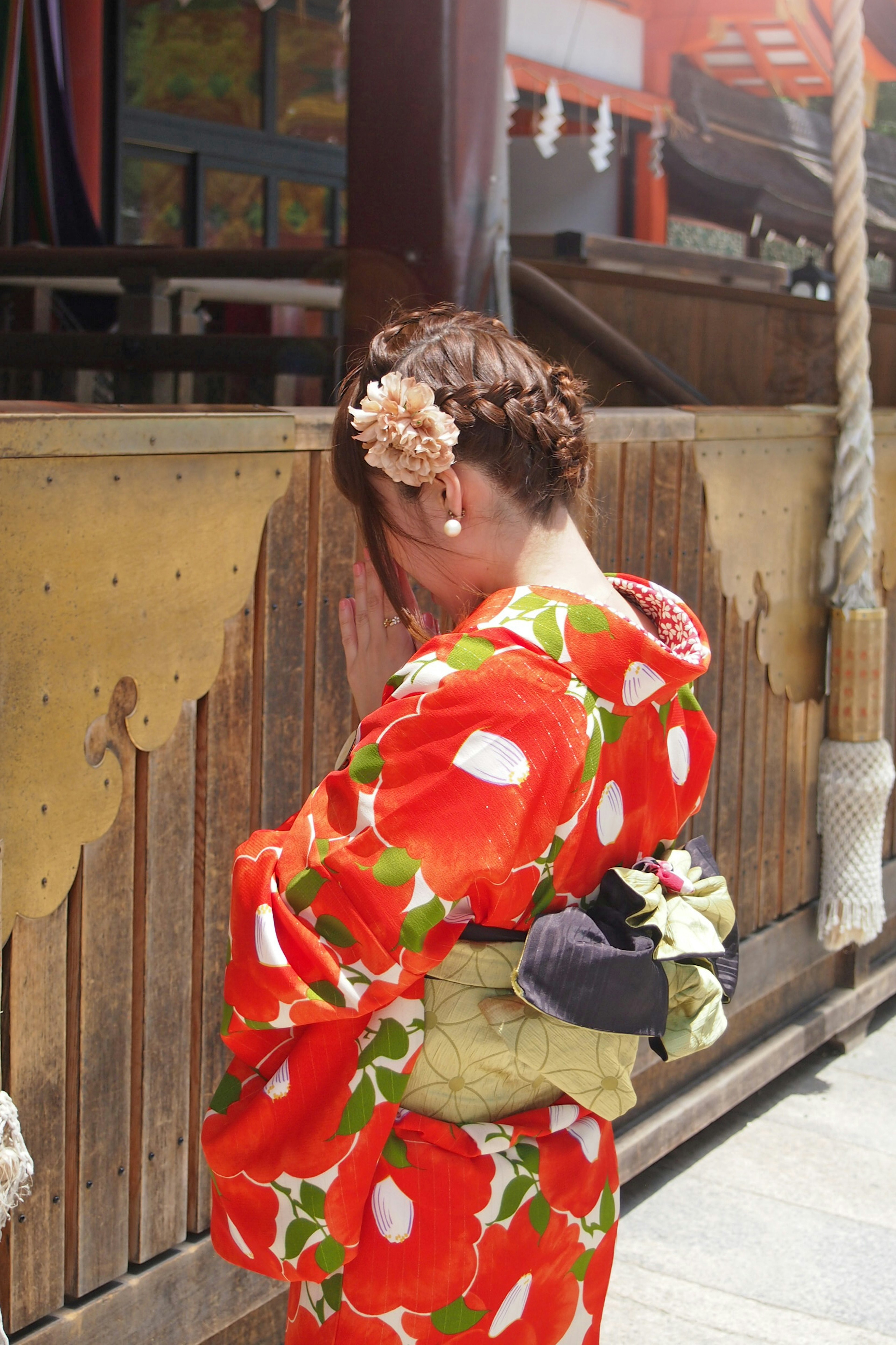 Mujer en kimono floral rojo ocultando su rostro