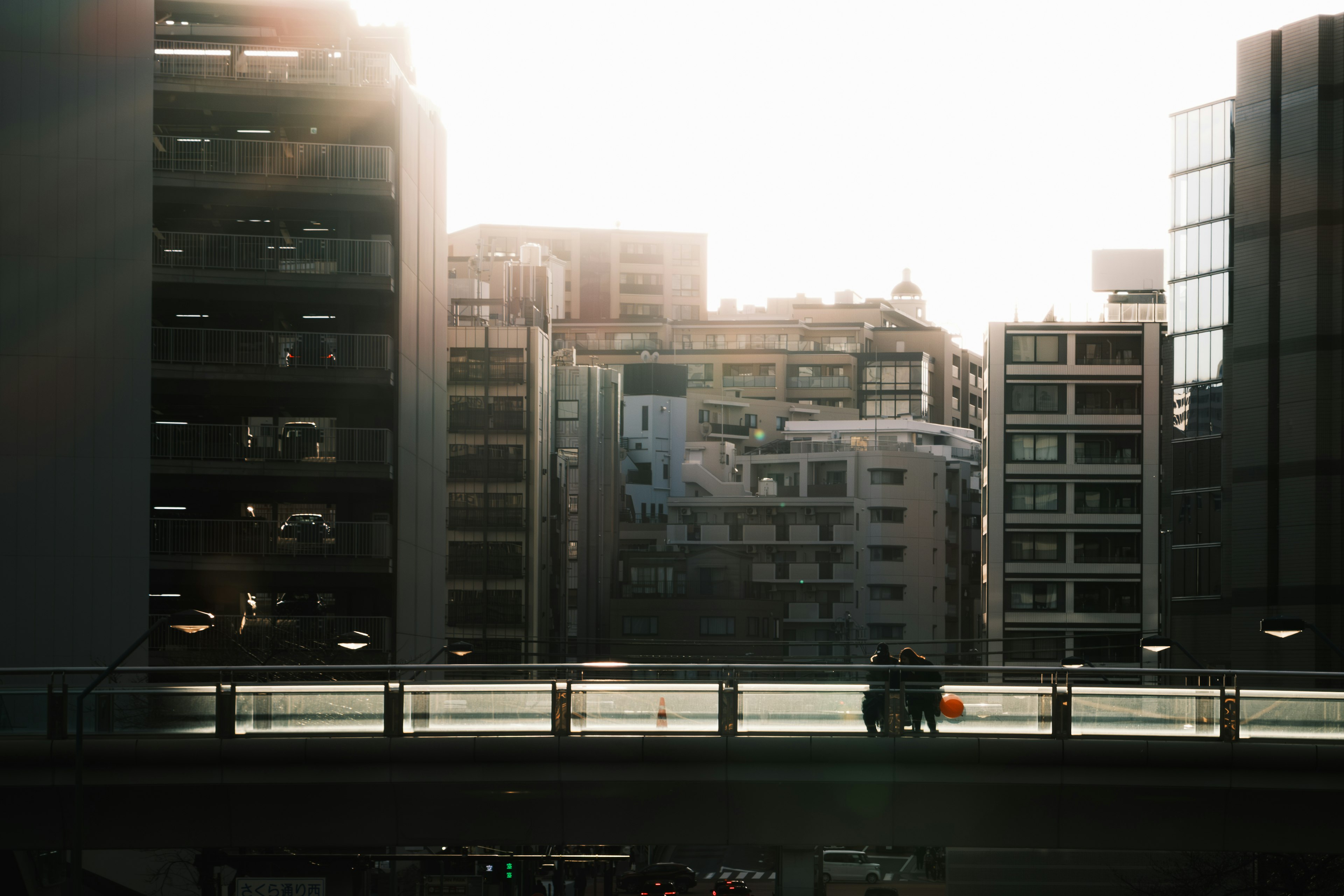 夕日に照らされた都市の風景と人々が歩く橋