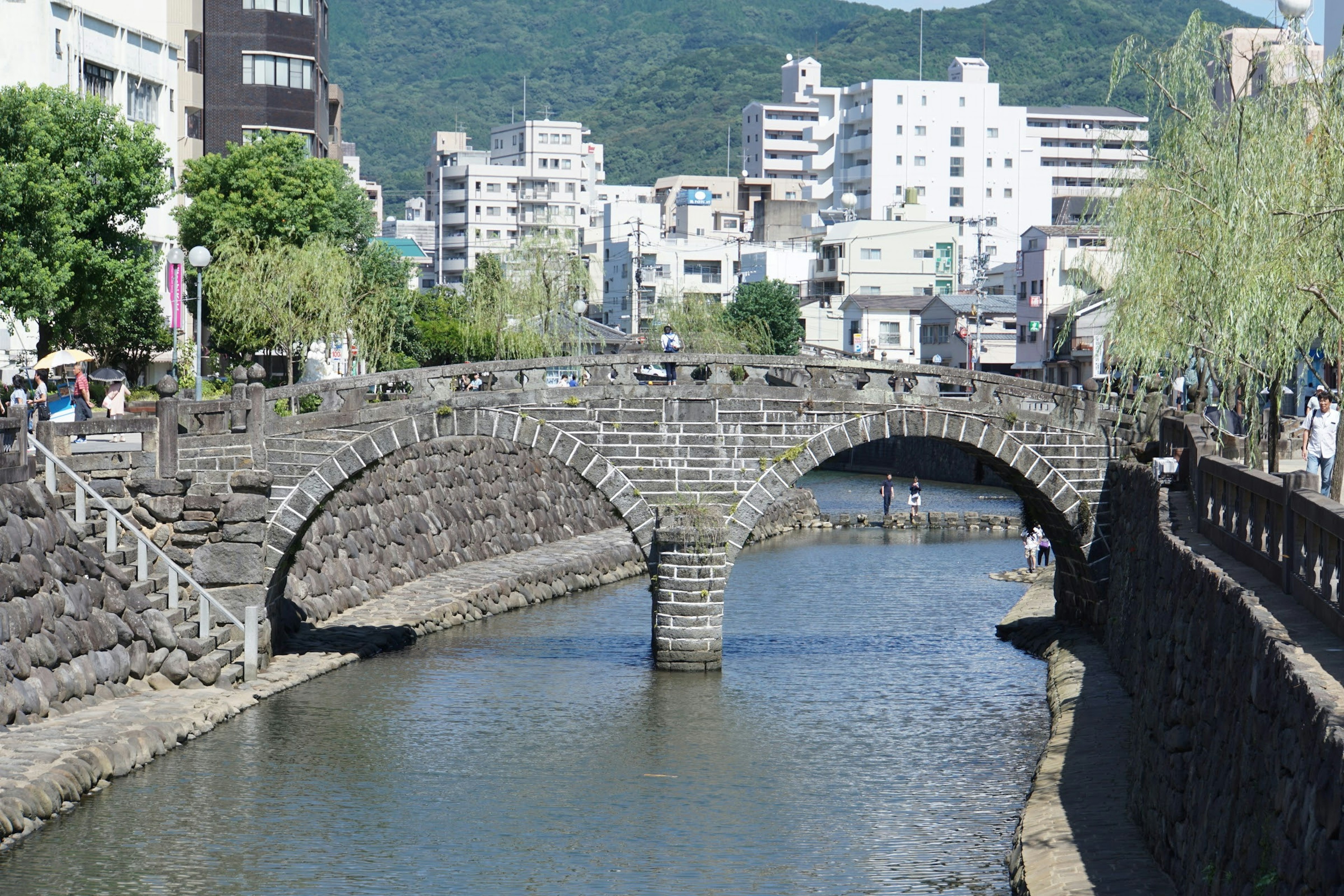 石拱桥横跨平静的河流，背景有建筑物