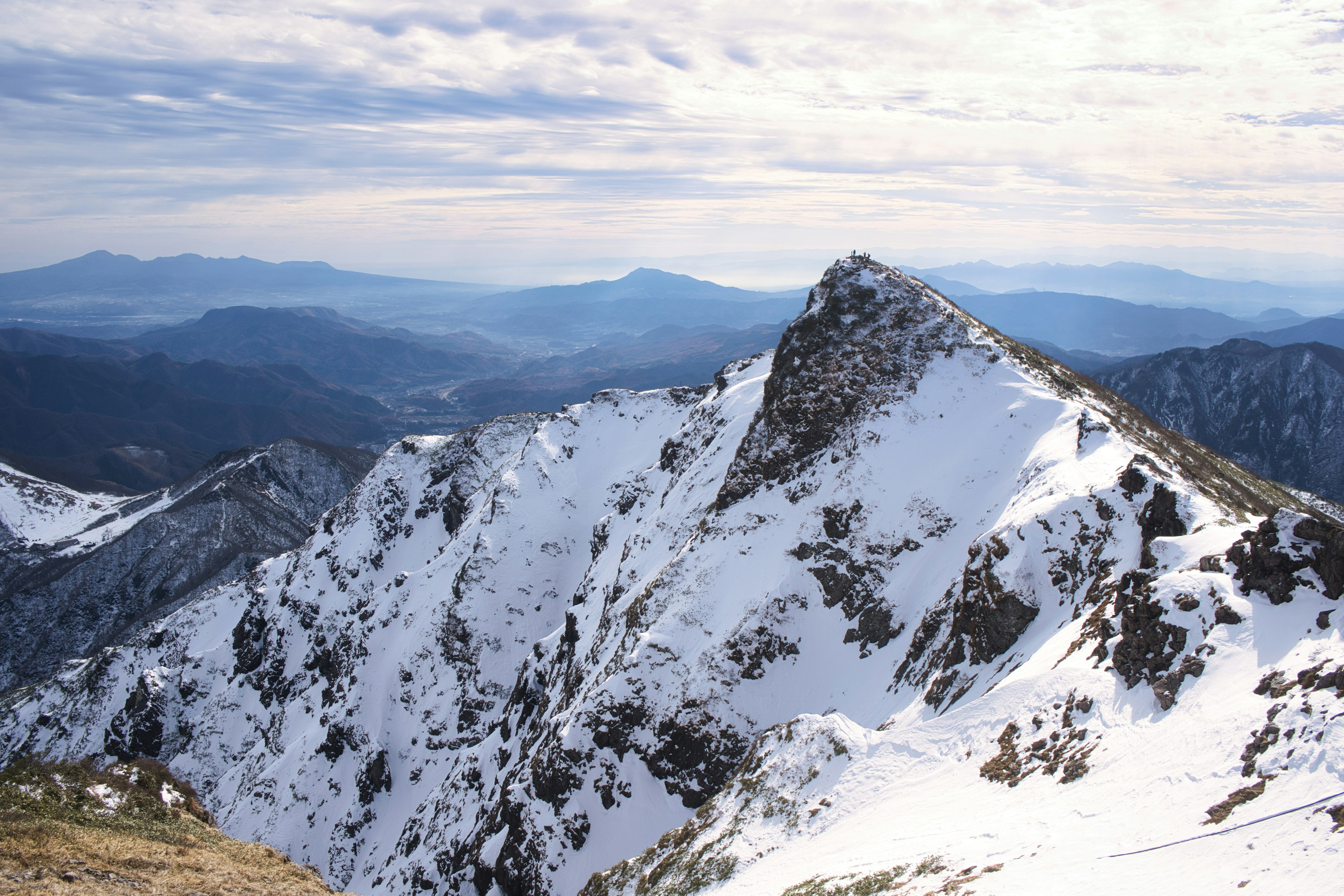 Punta di montagna coperta di neve con catena montuosa in lontananza