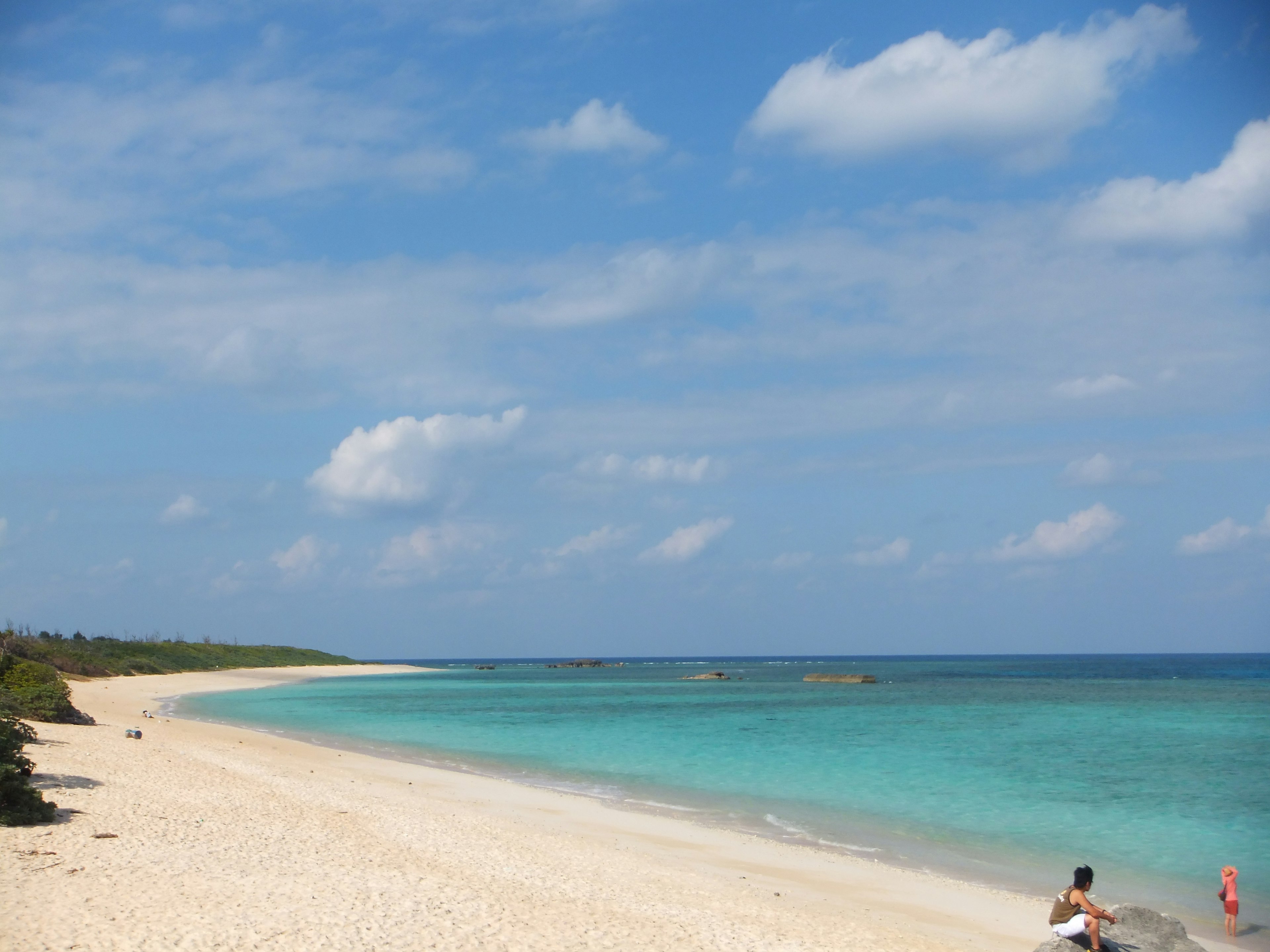 Pemandangan pantai yang indah dengan laut biru dan pasir putih di bawah langit cerah