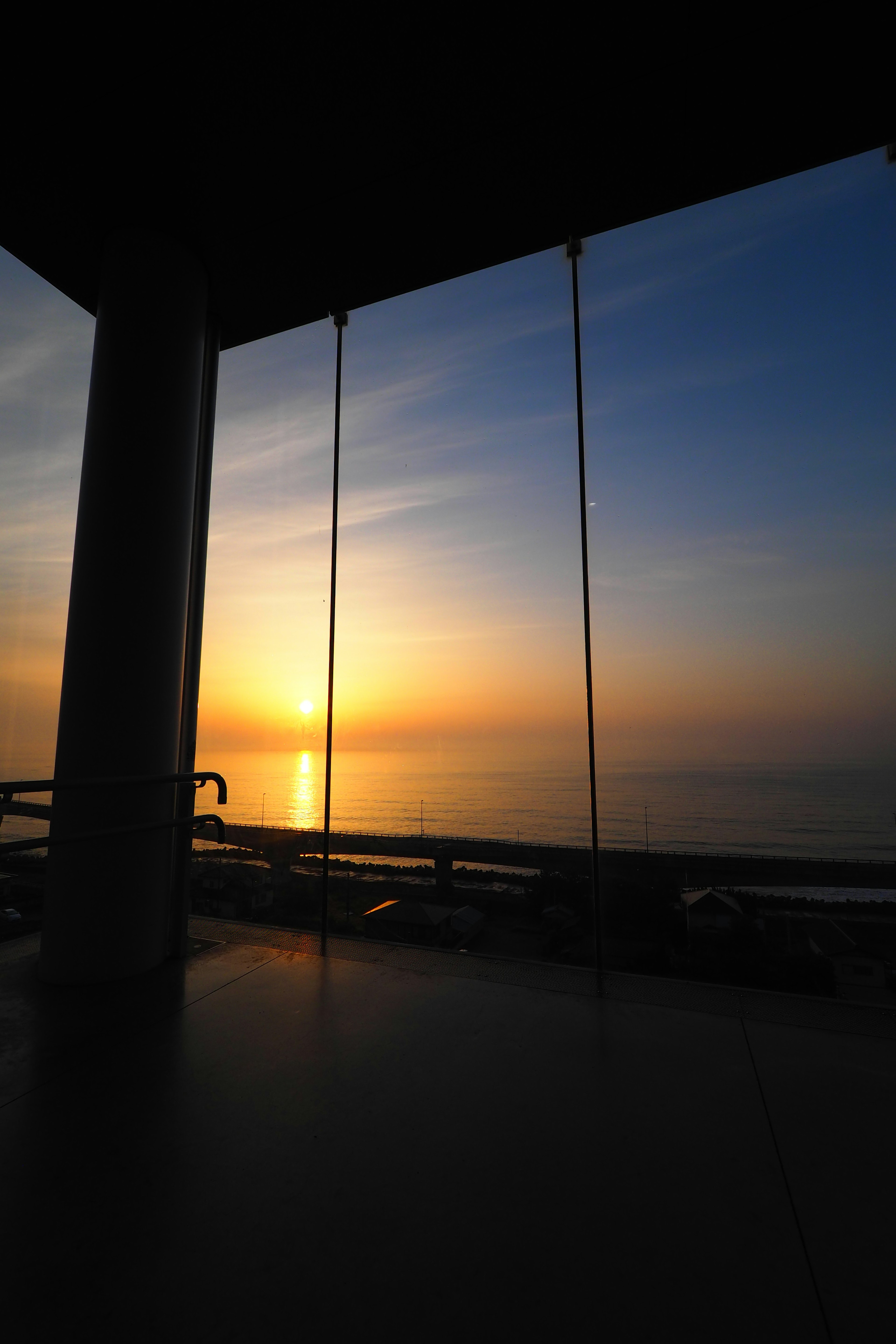 Schöner Blick auf den Sonnenuntergang über dem Meer mit hängenden Stühlen in einem offenen Raum