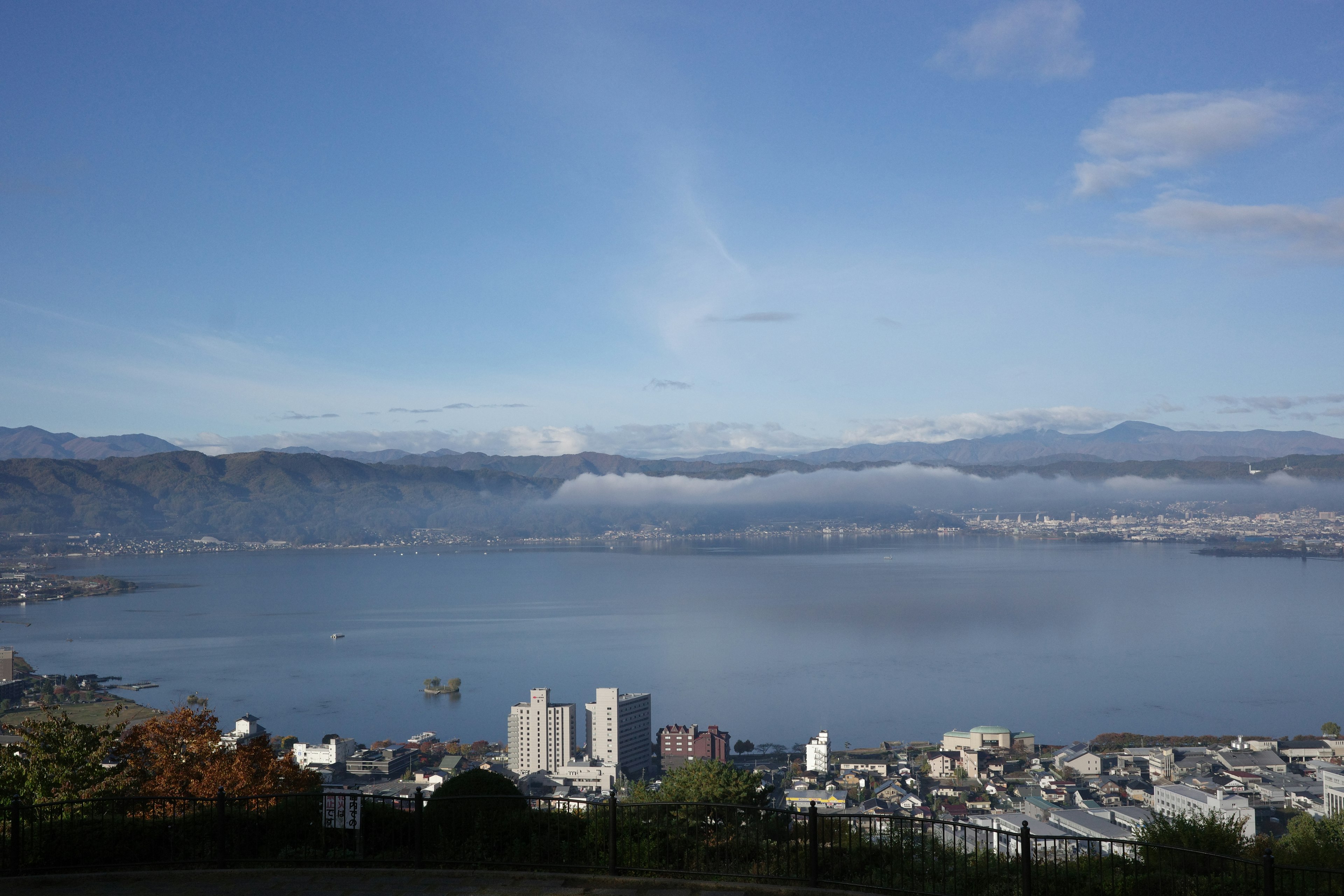 Panoramablick auf eine Stadt umgeben von einem schönen See und blauem Himmel