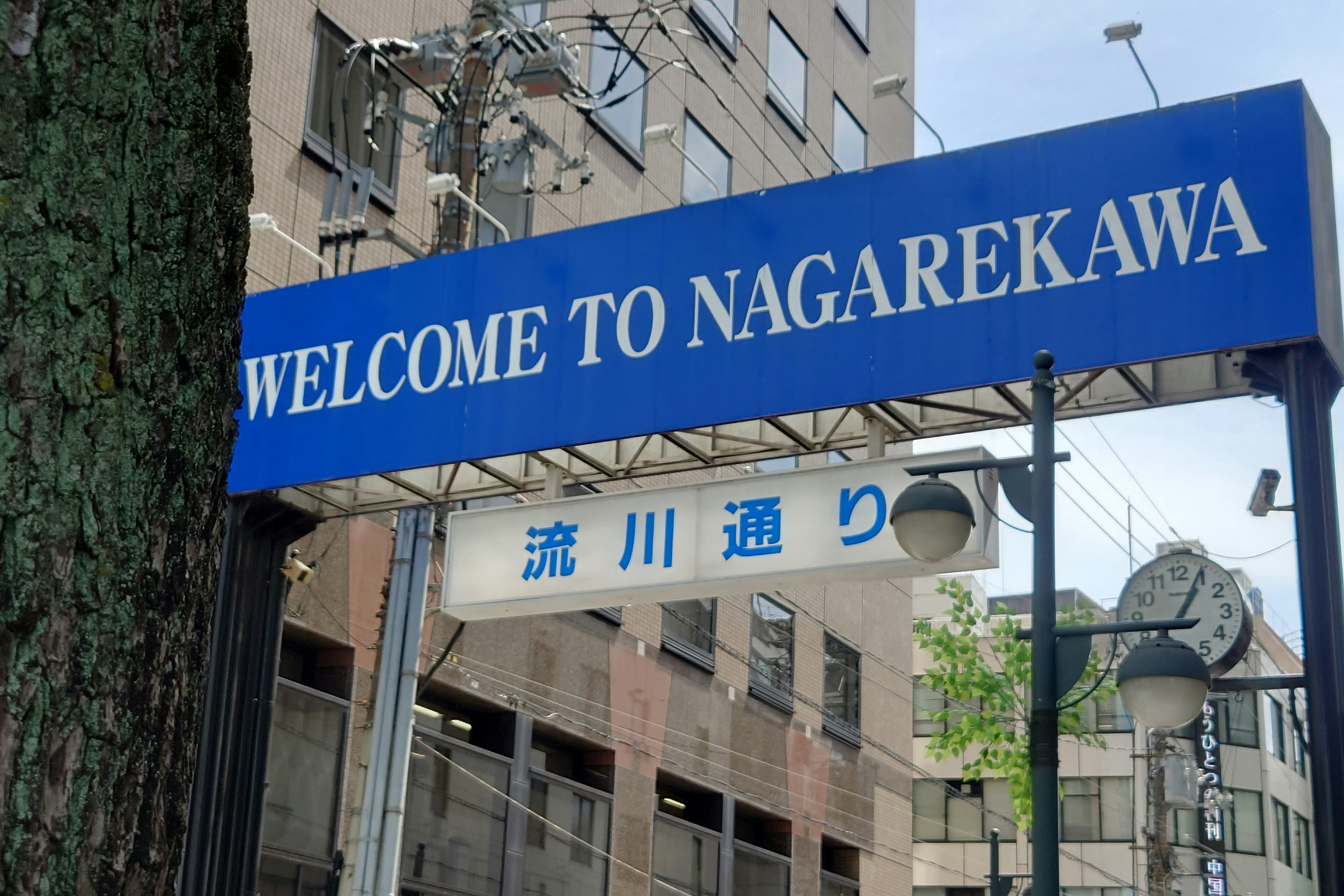 Panneau de bienvenue à Nagarekawa avec un paysage urbain