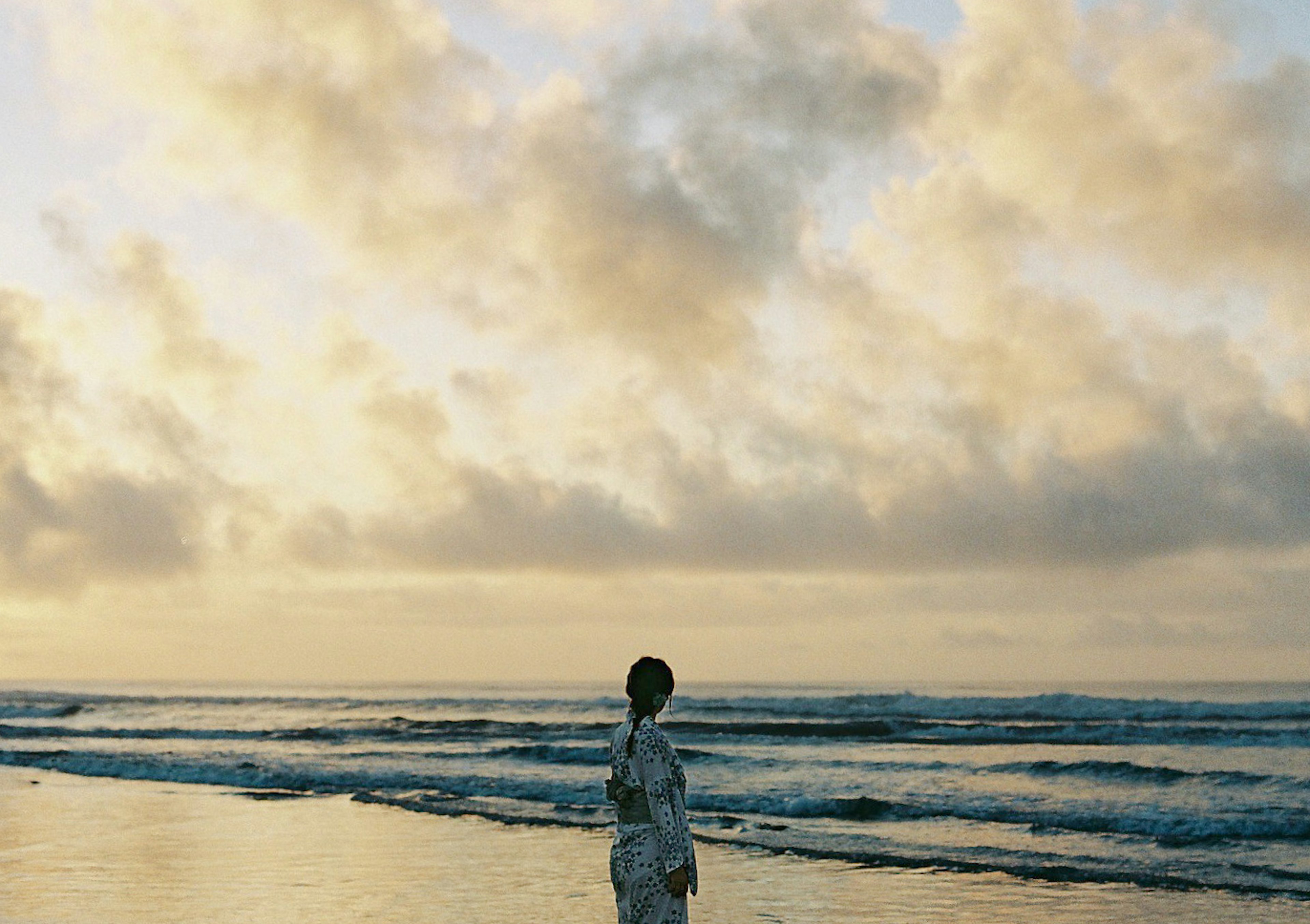 海岸で夕日を背に立つ女性のシルエット