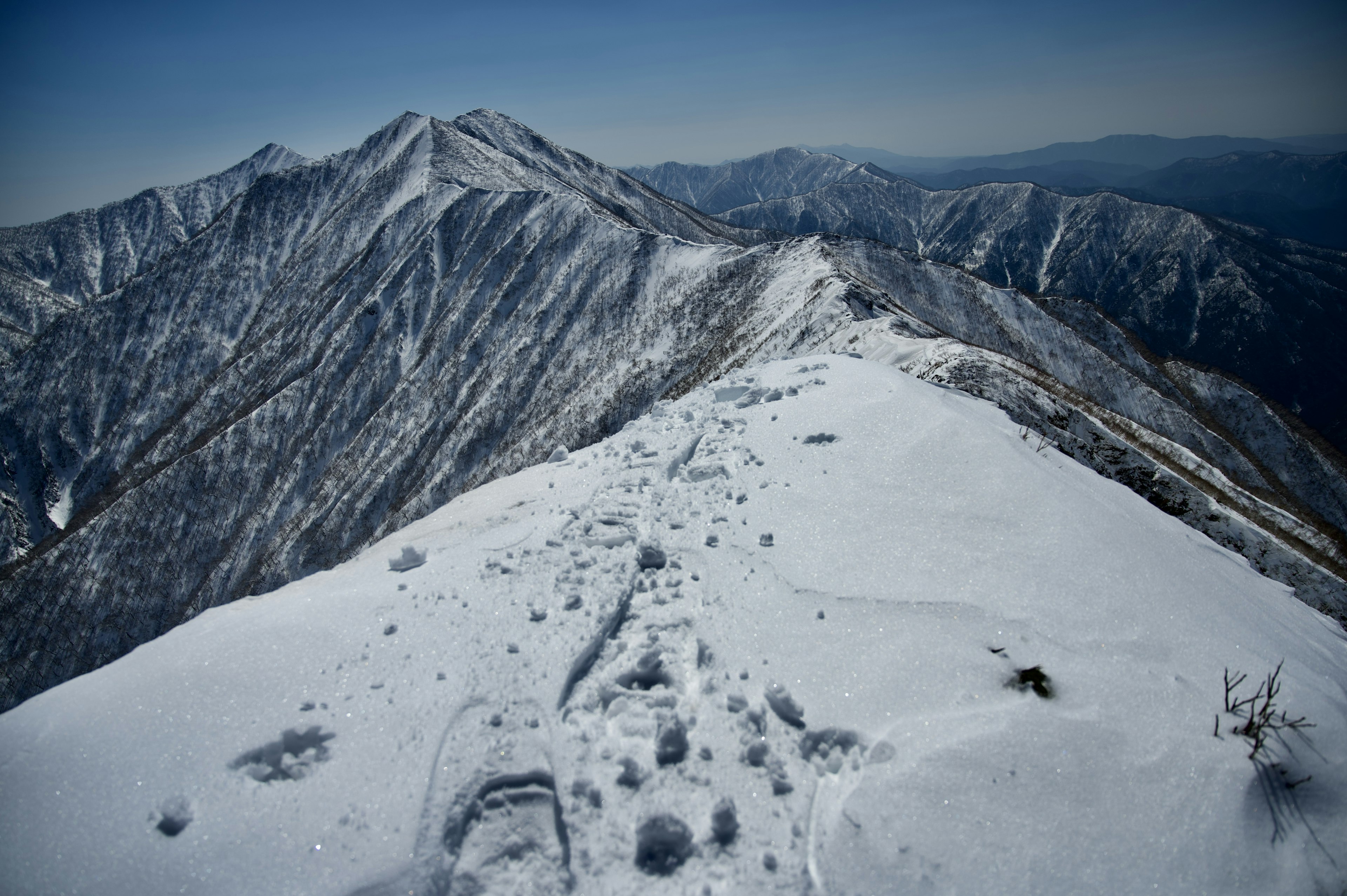 Paesaggio di cima montuosa coperta di neve con catene montuose lontane