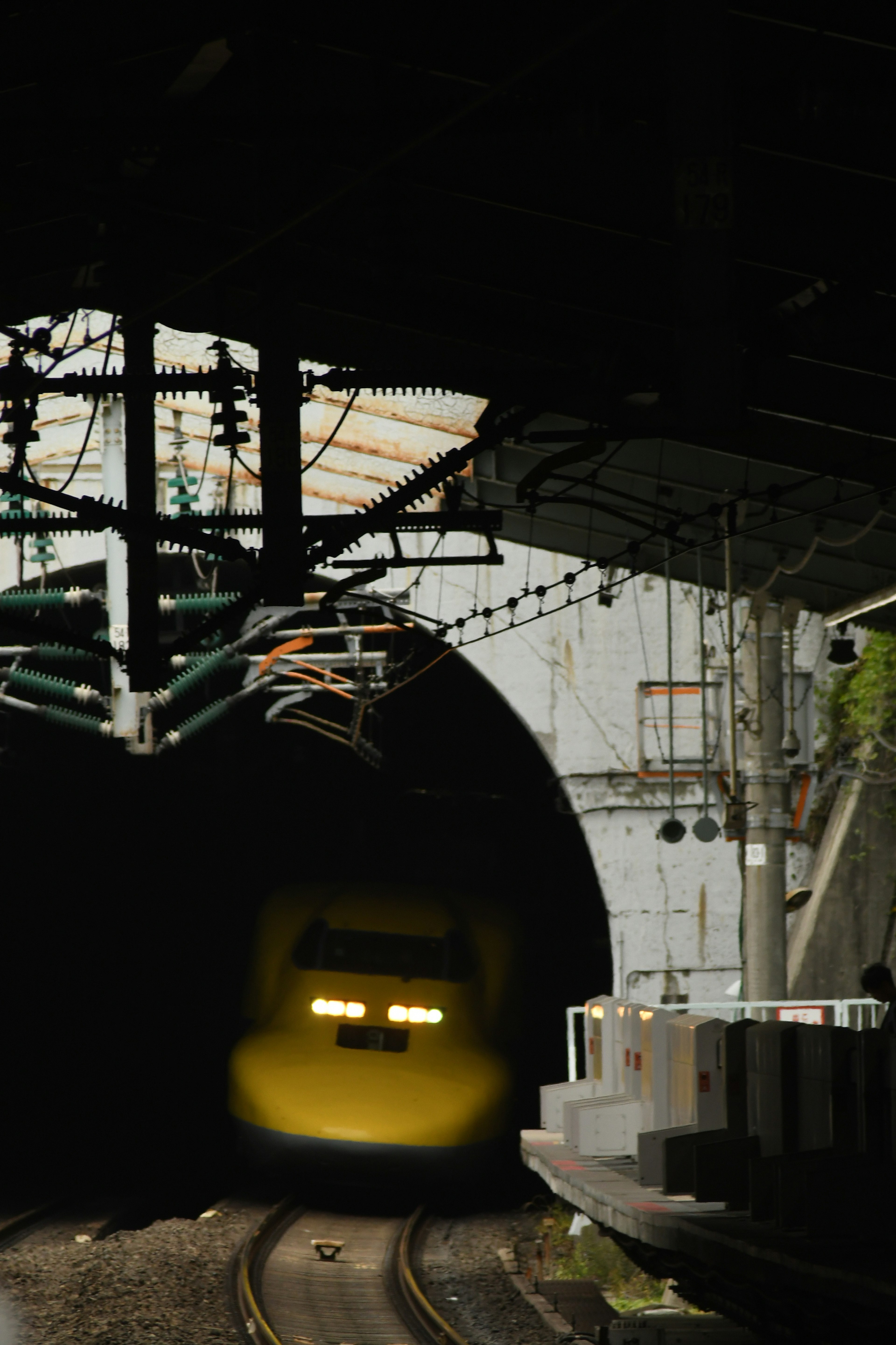 Yellow Shinkansen train emerging from a tunnel