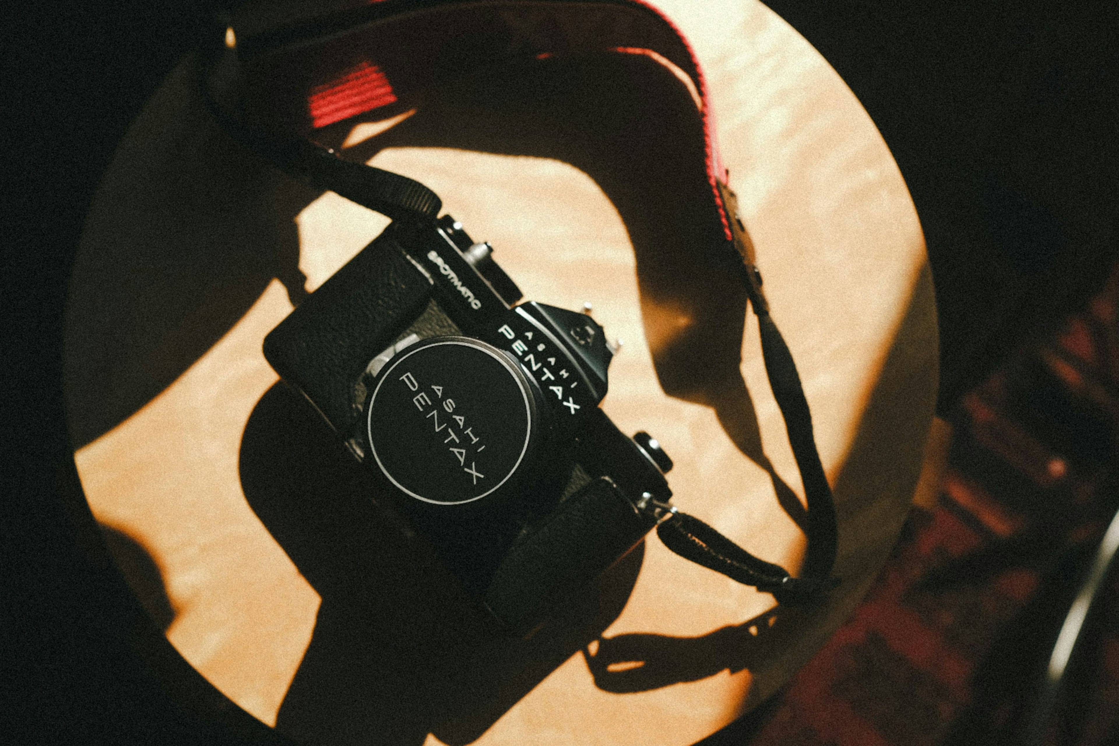 A camera with a strap placed on a wooden table