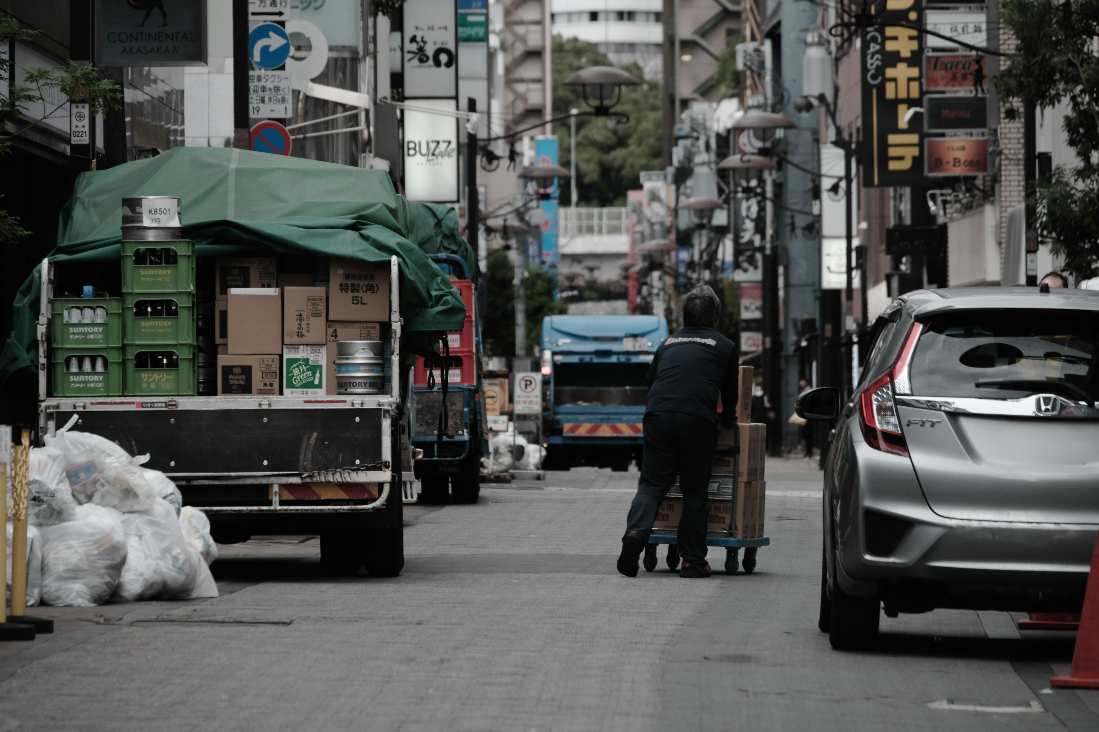 狭い通りで荷物を運ぶ作業員とトラックの風景