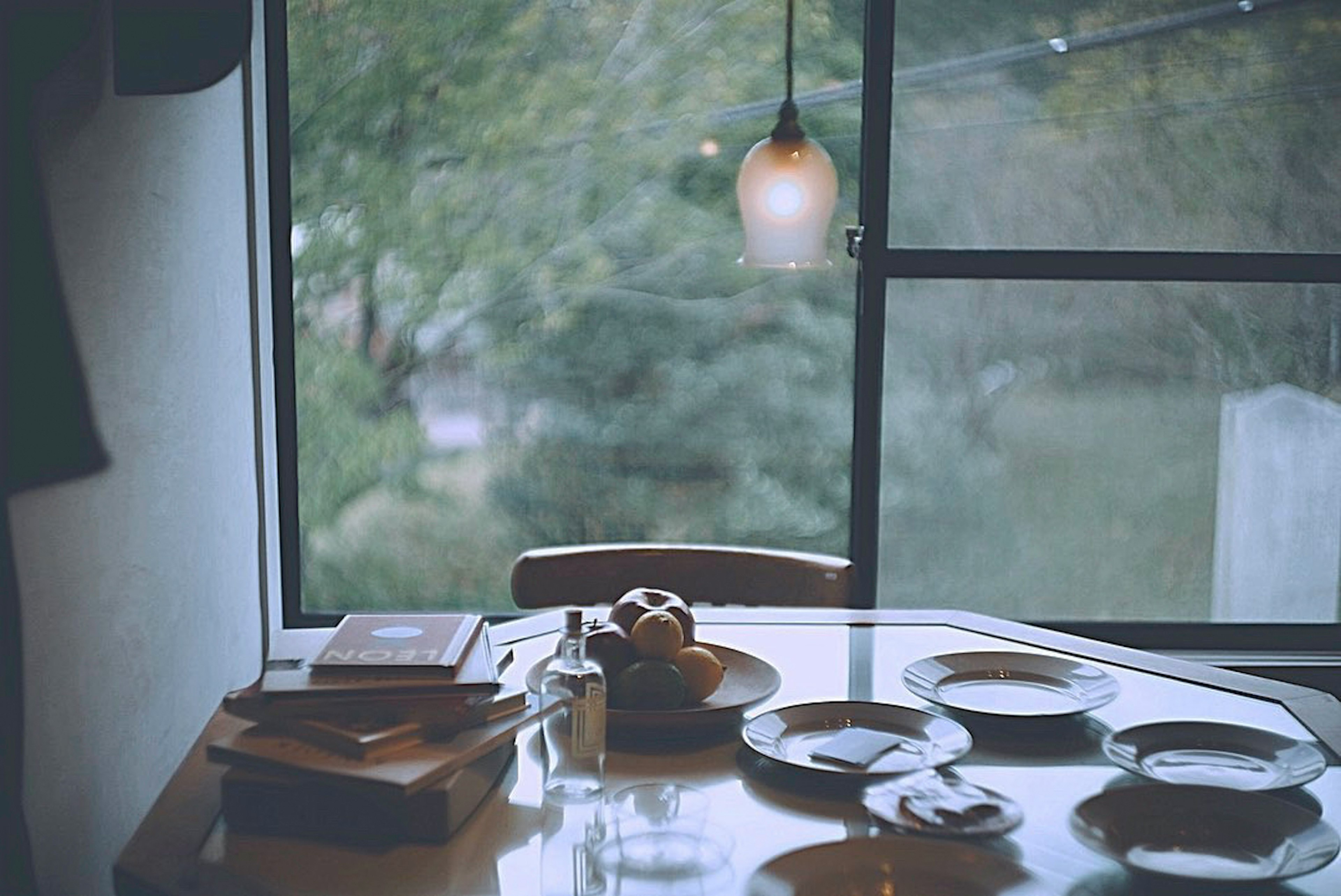 A cozy table setting with books and dishes on a wooden table near a window