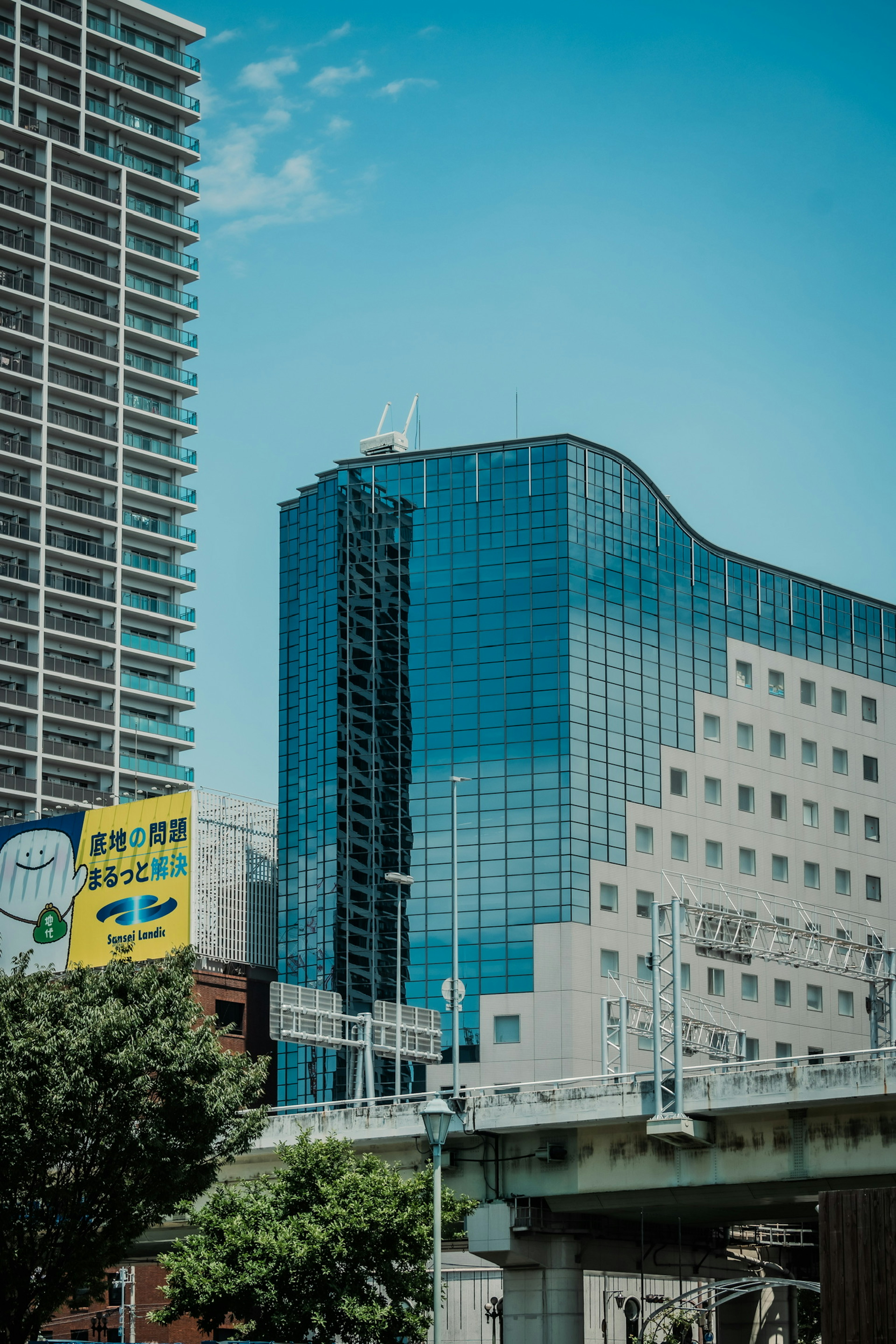 Gedung pencakar langit modern dengan kaca reflektif di bawah langit biru