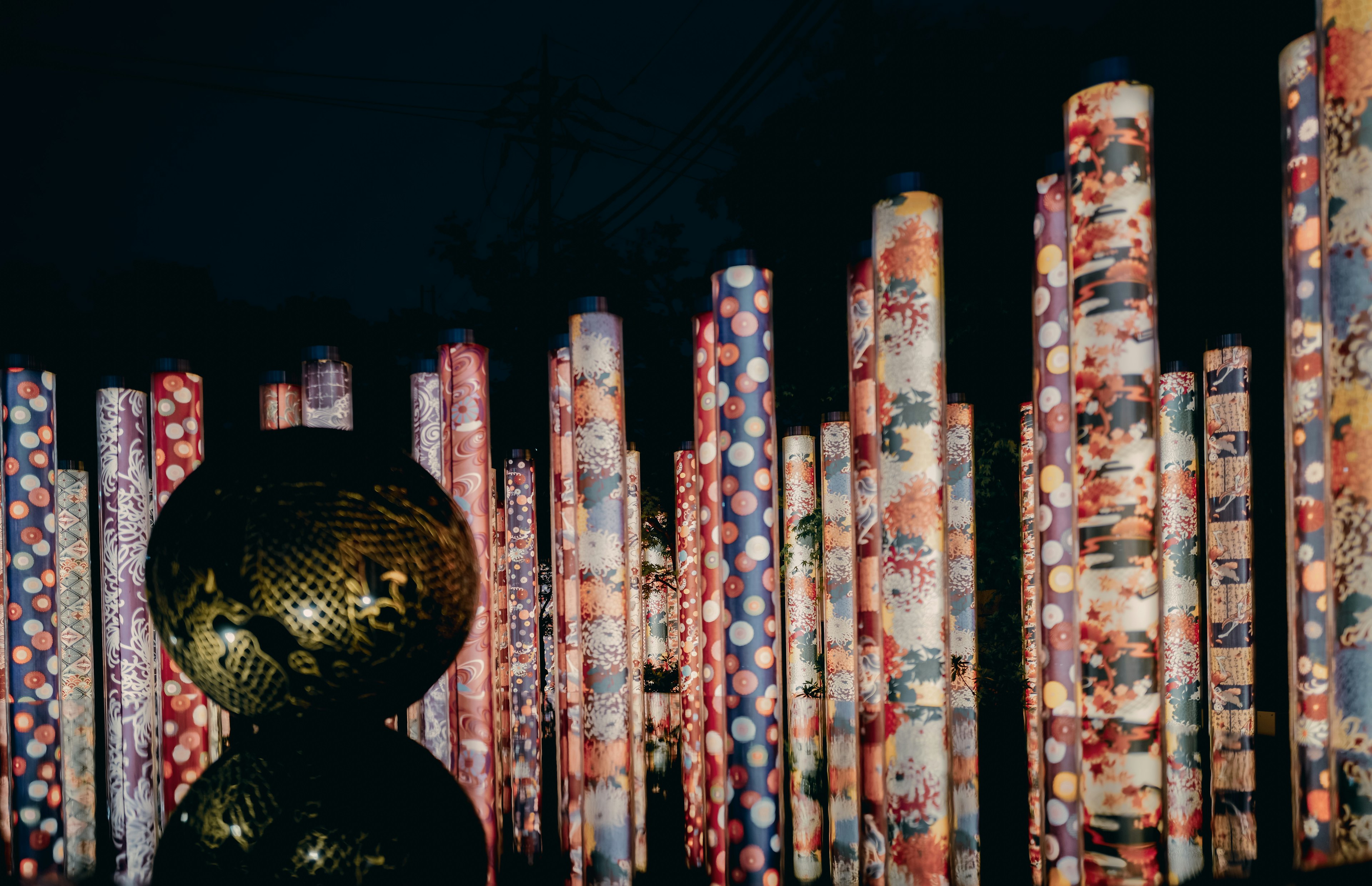 Colorful patterned pillars illuminated at night with a golden object in the foreground