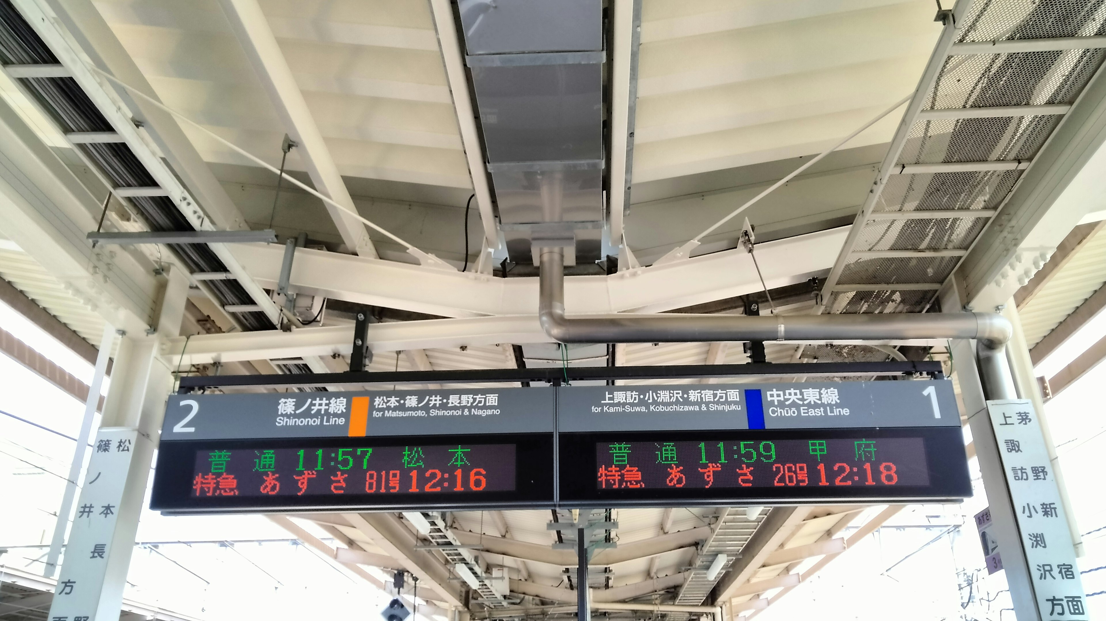 Digital display boards at a train station platform showing train schedules