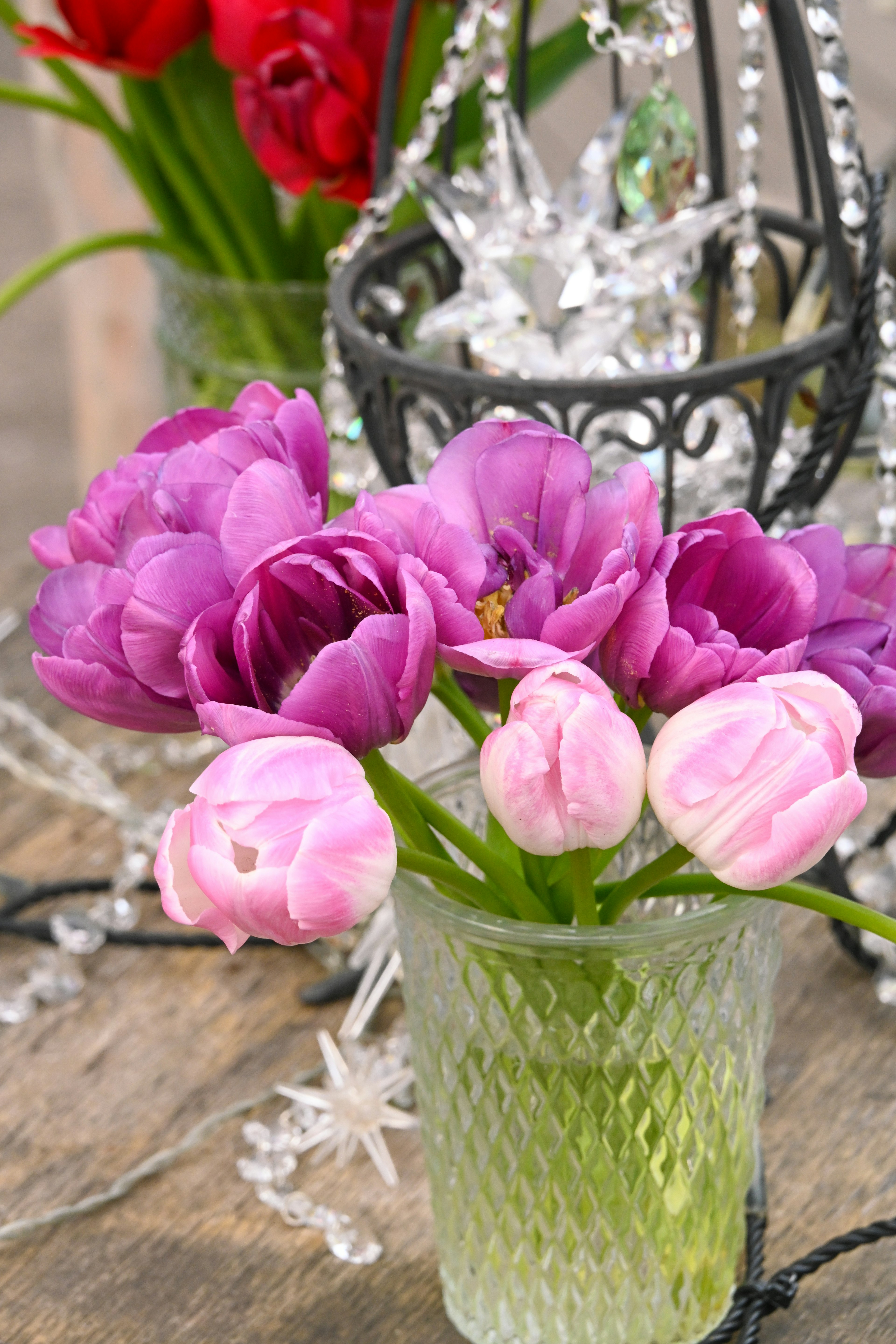 Glass vase filled with purple and pink tulips alongside crystal decorations