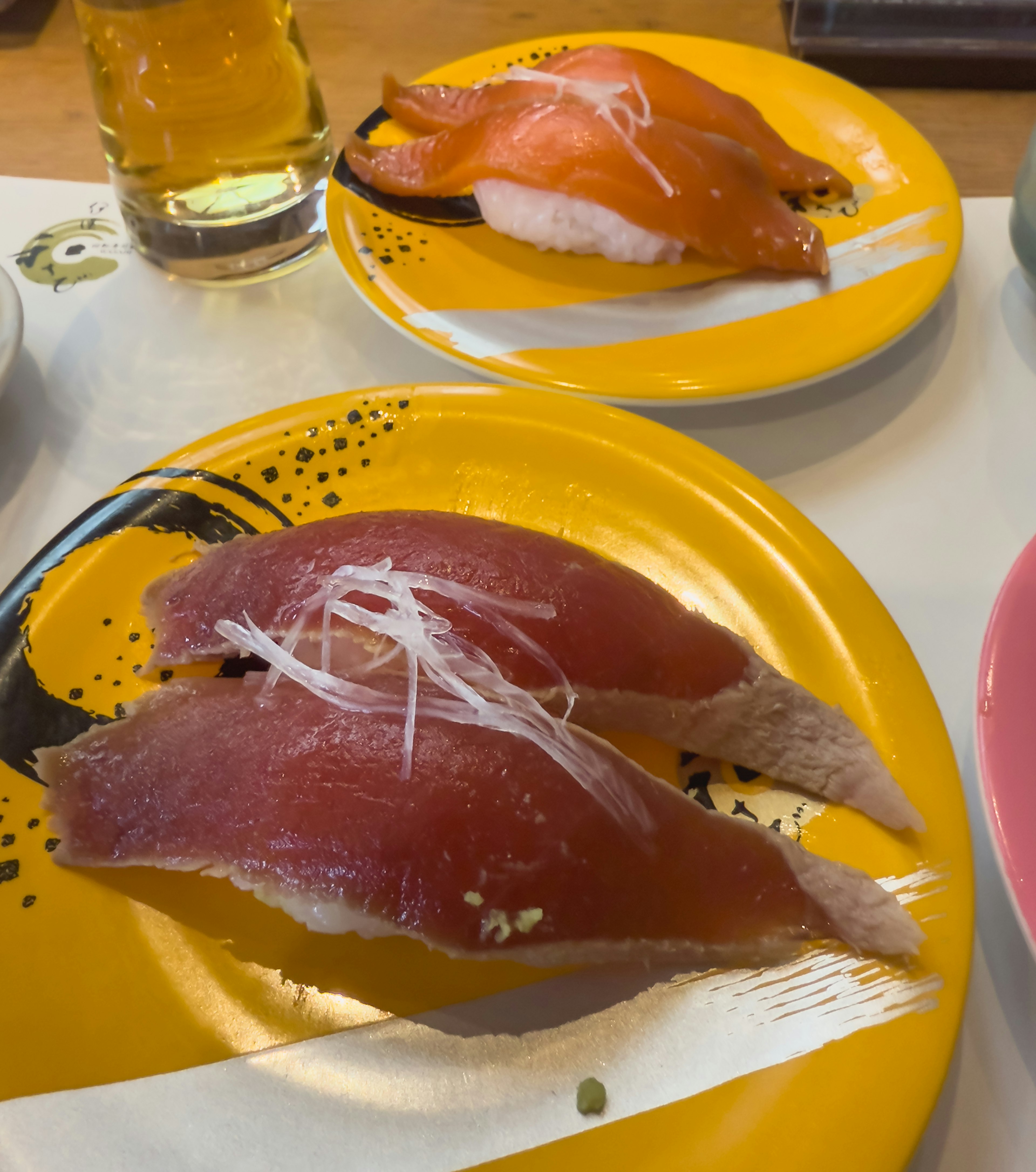 Un plato de sushi que presenta atún y salmón en un plato amarillo vibrante