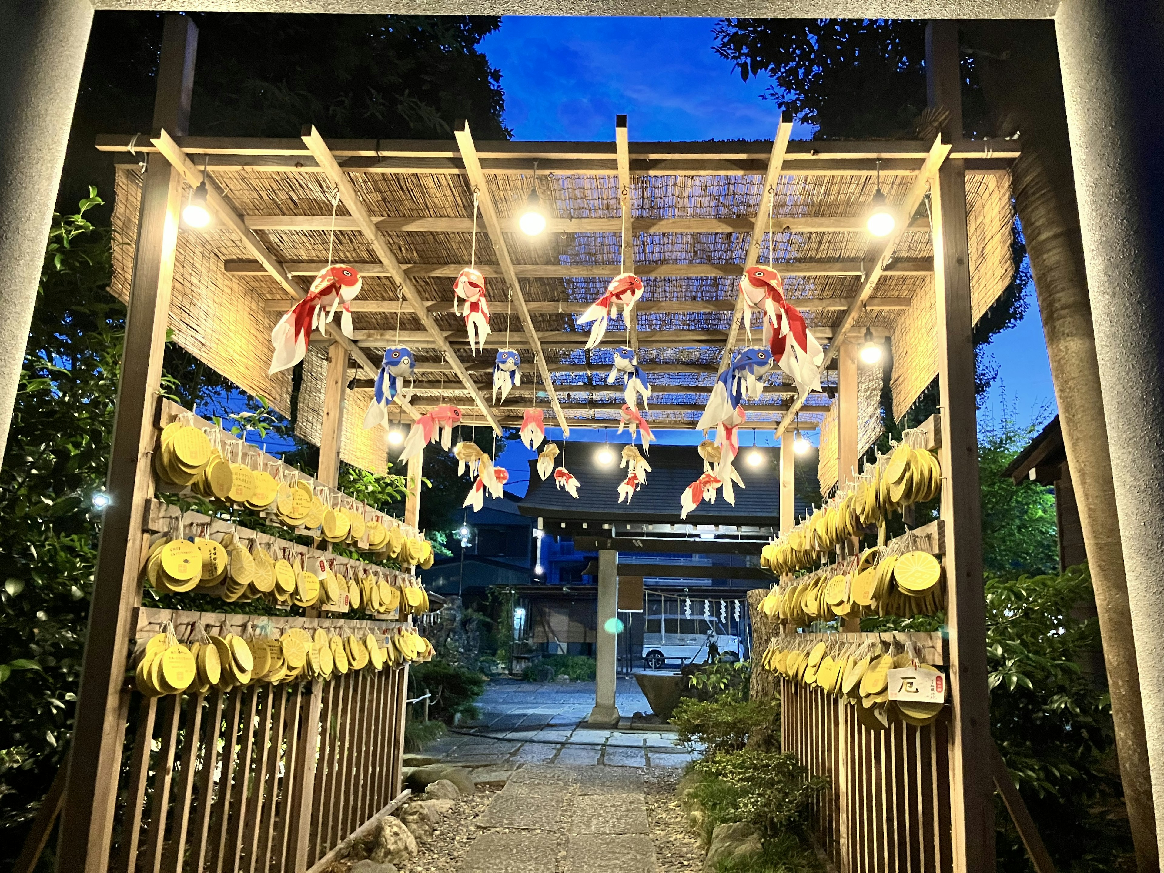 Entrance of a shrine at night with lanterns and yellow decorations