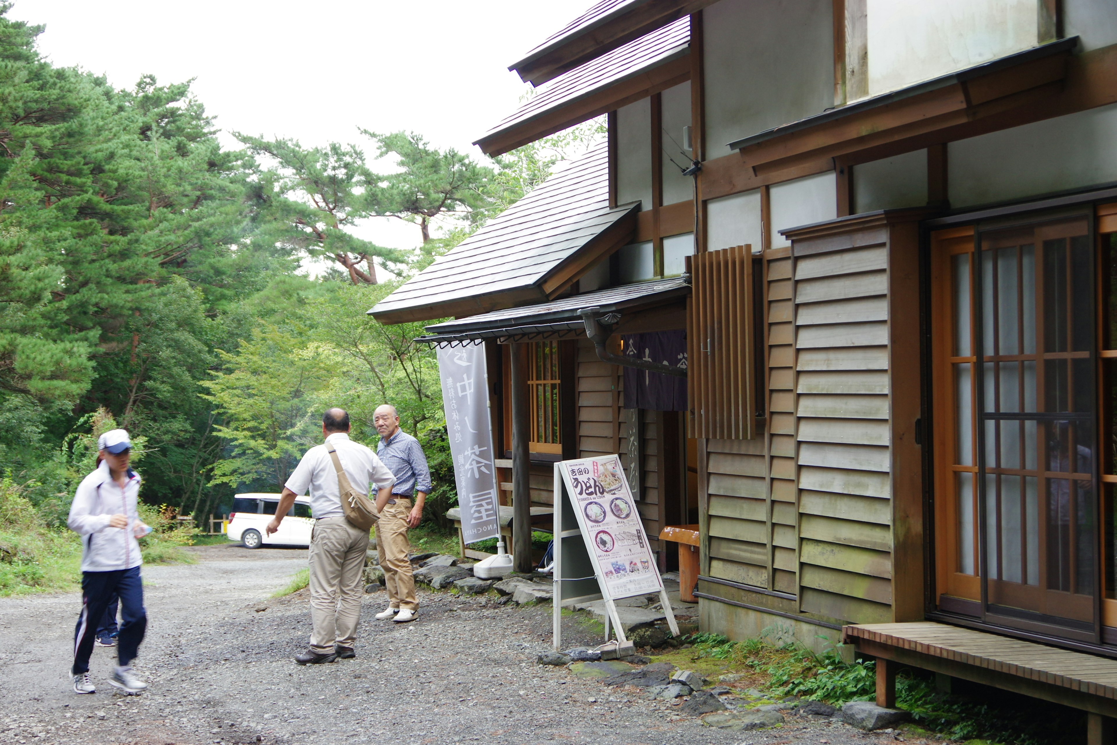 Menschen vor einem traditionellen japanischen Gebäude umgeben von Natur