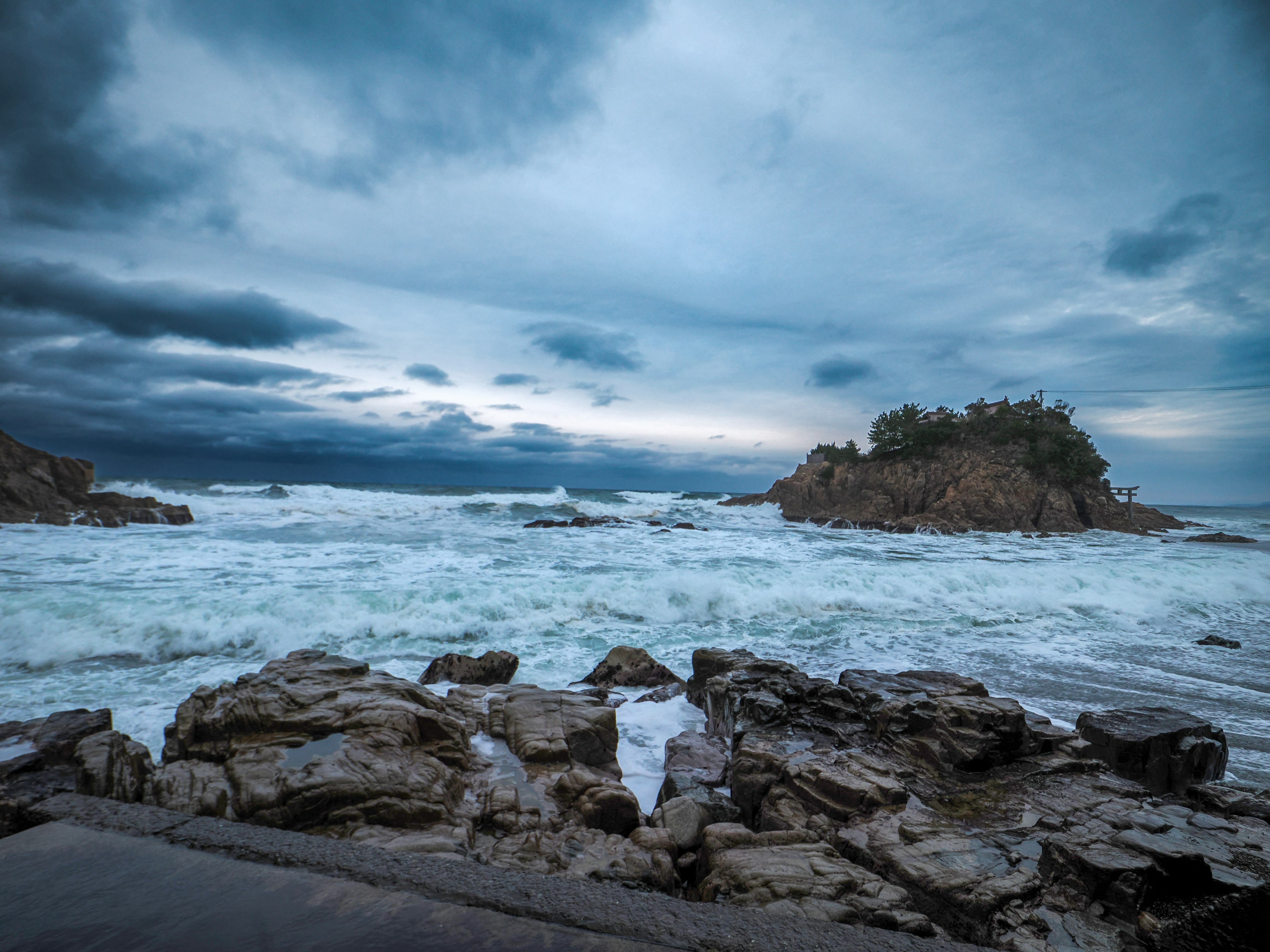 Rough sea and rocky landscape under a dark cloudy sky