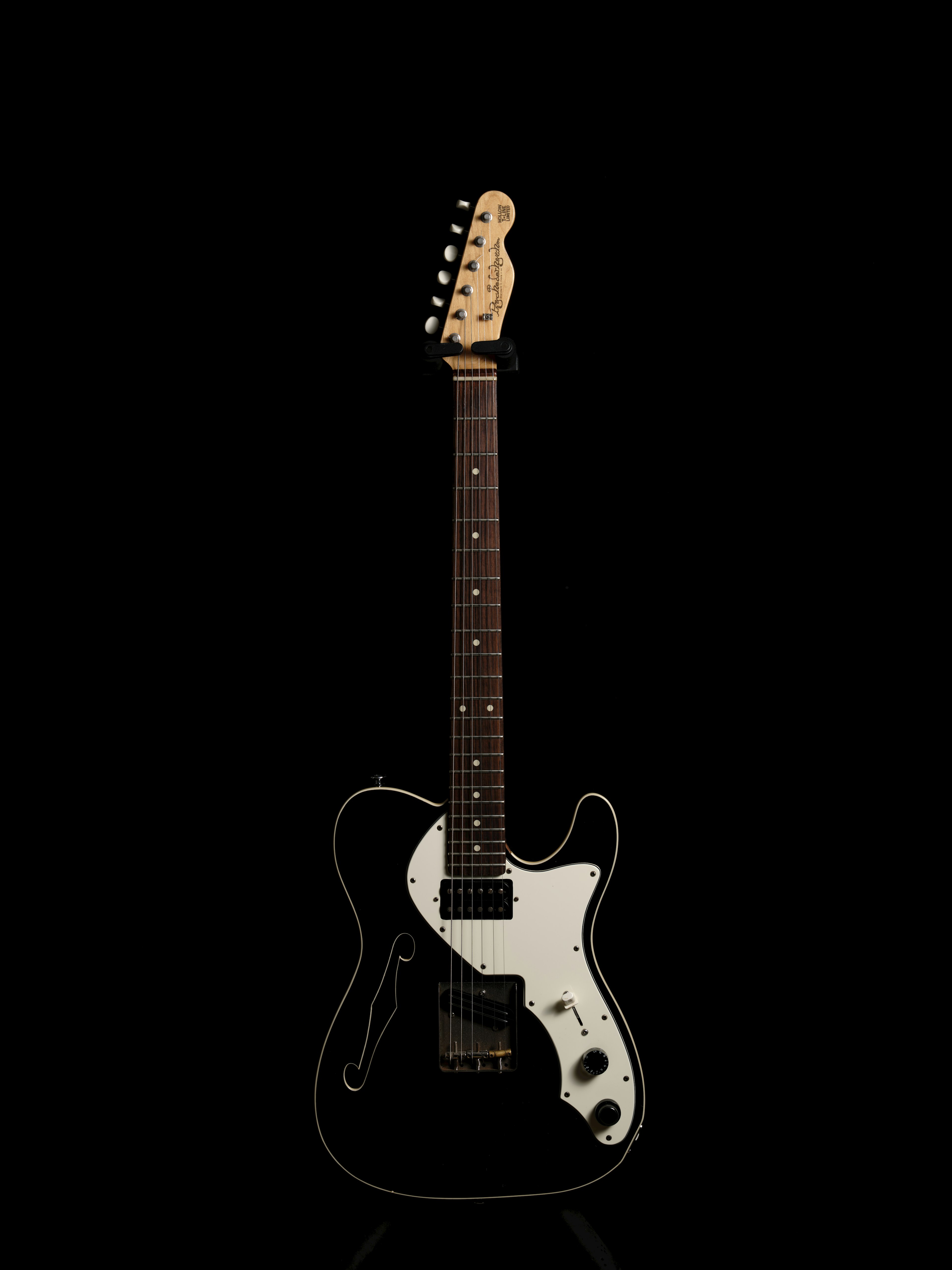 Electric guitar standing against a black background featuring a black body with white accents