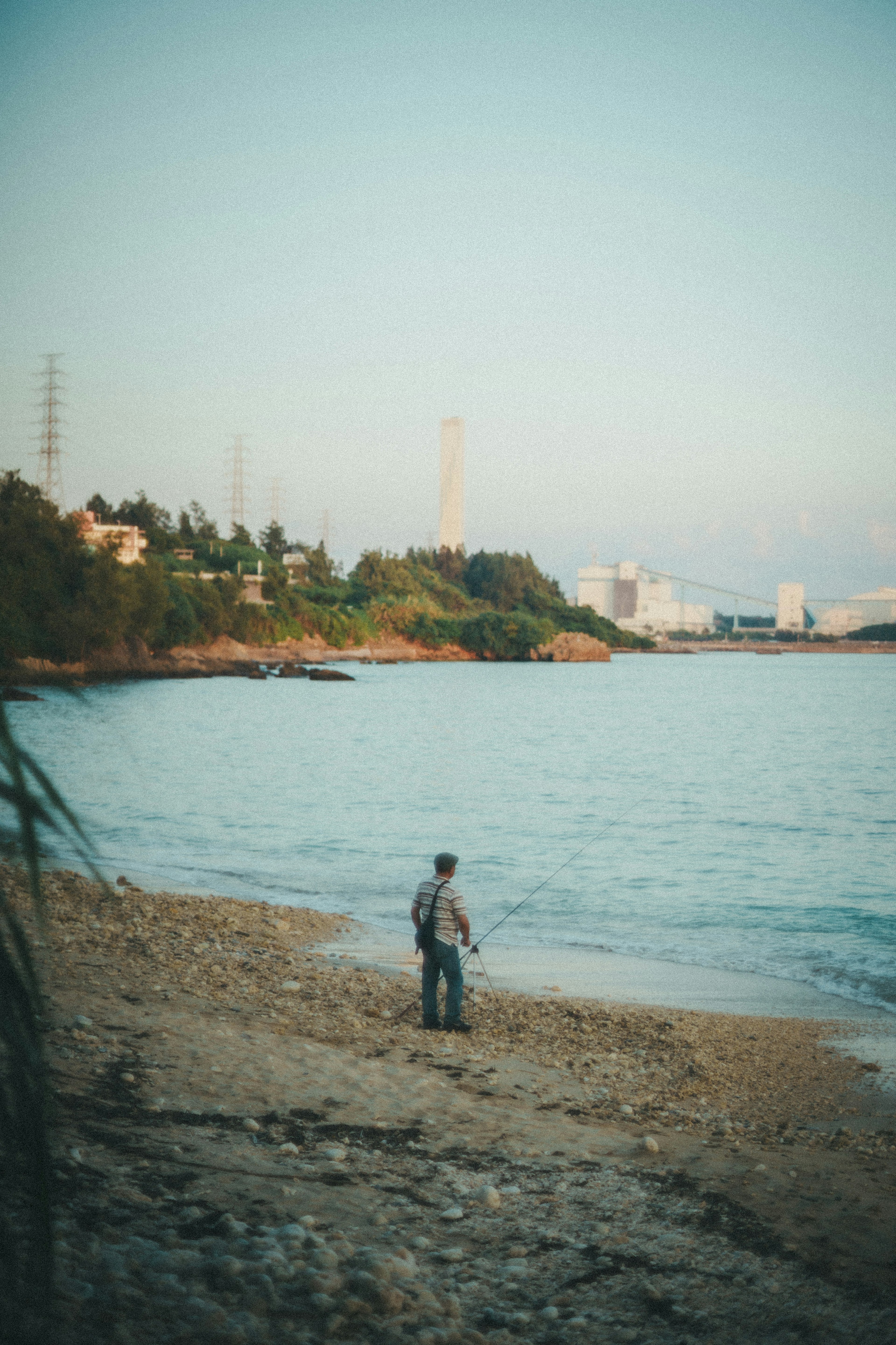 Un hombre pescando en la orilla con edificios de fondo