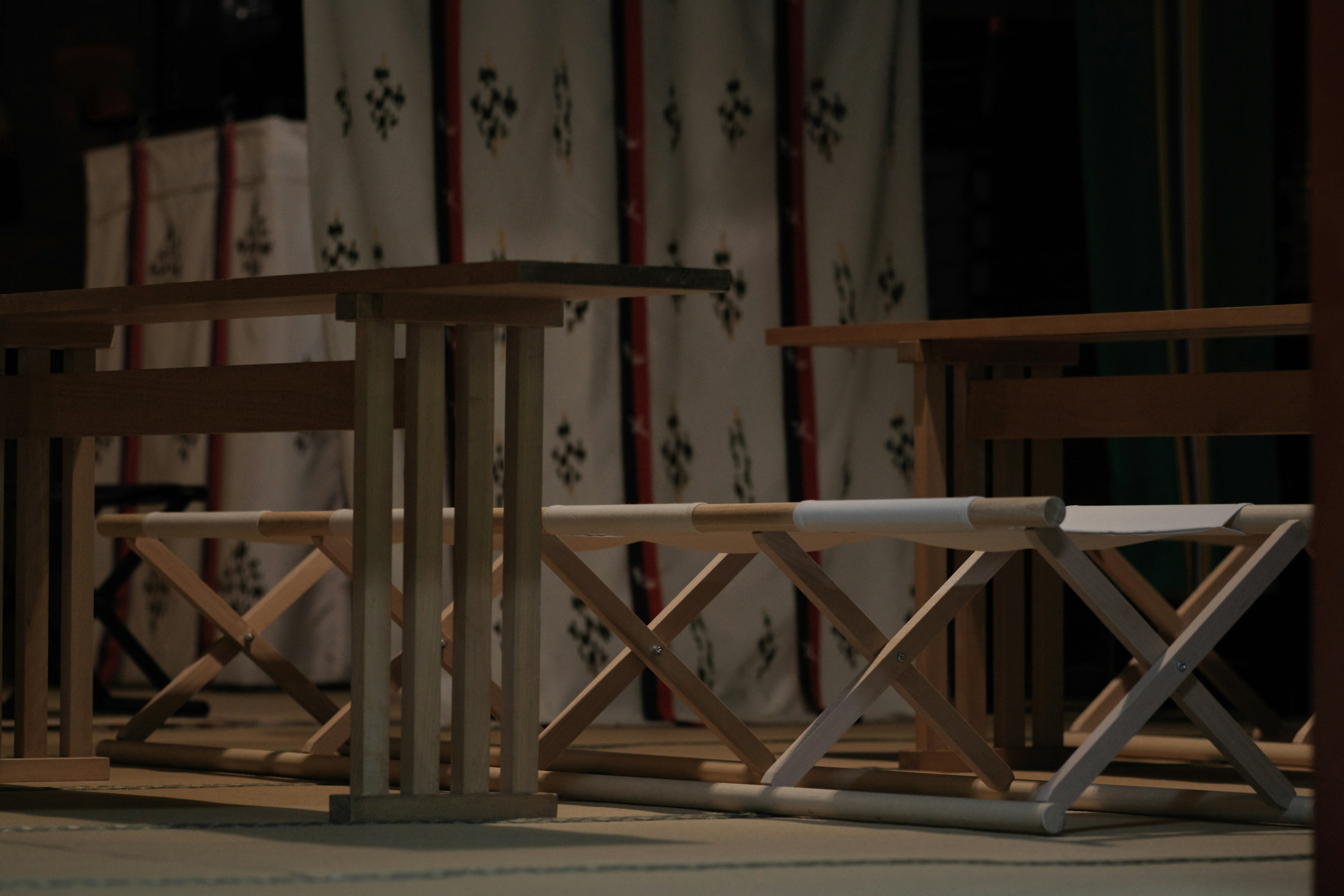 Simple wooden table and benches arranged with a fabric backdrop