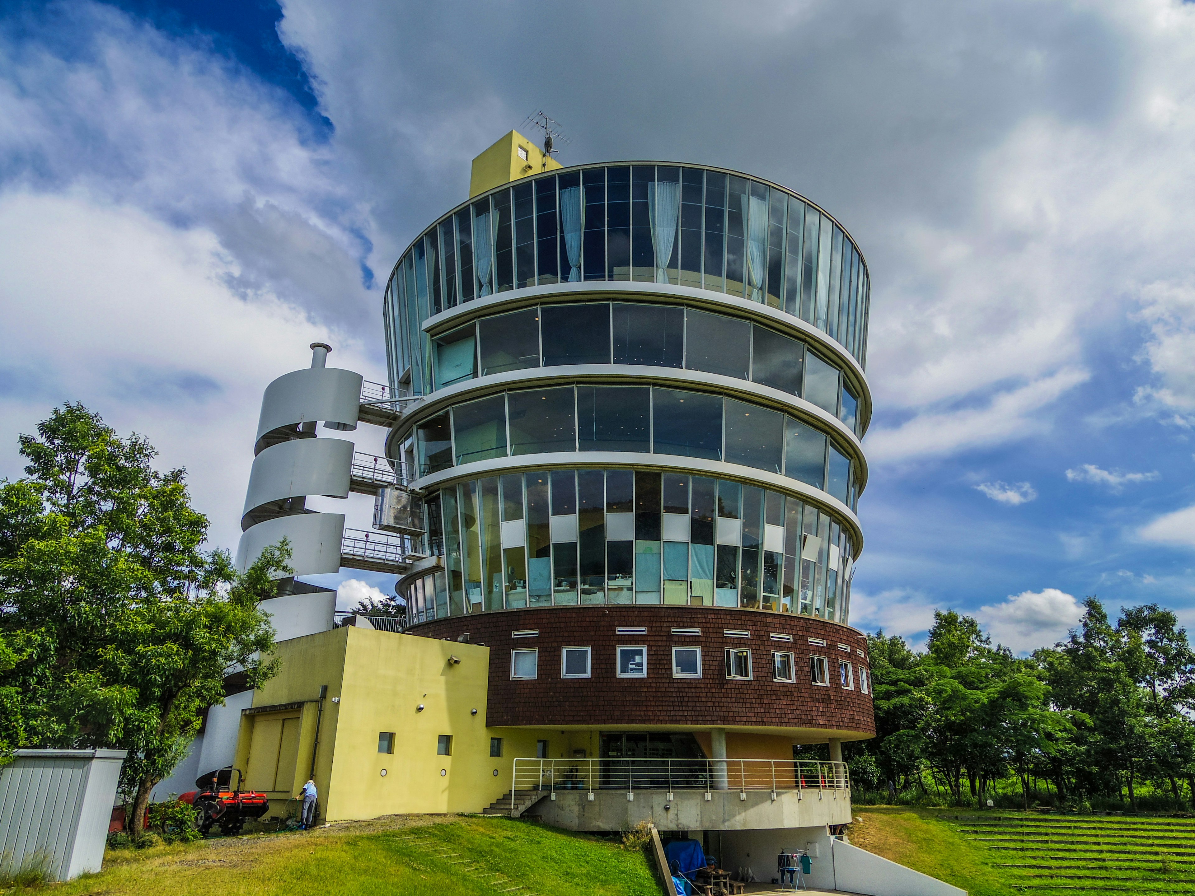 Modern cylindrical building with large glass windows and lush greenery