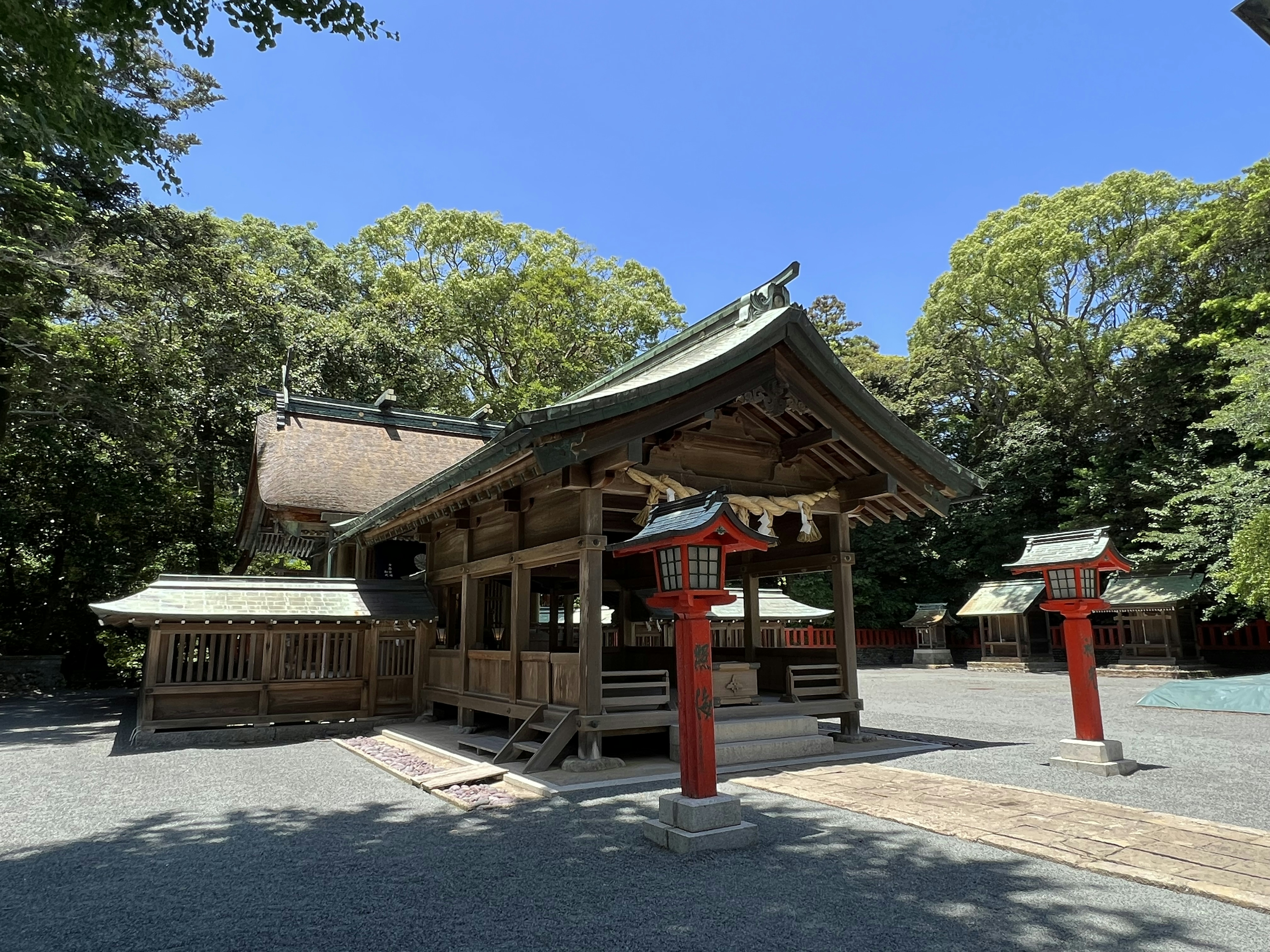 緑の木々に囲まれた伝統的な神社の建物と赤い鳥居