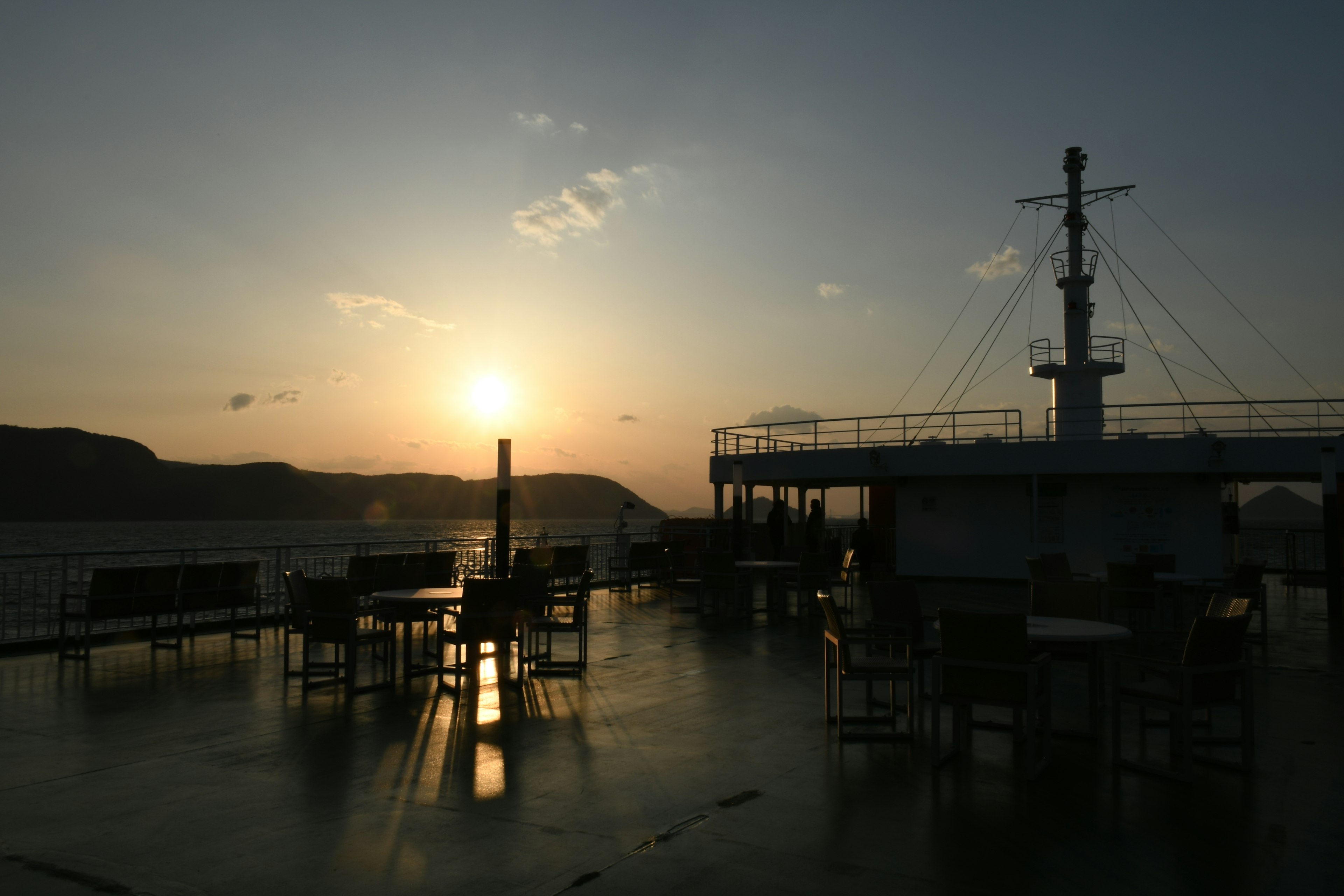 Sonnenuntergang über einem Schiffdeck mit Tischen