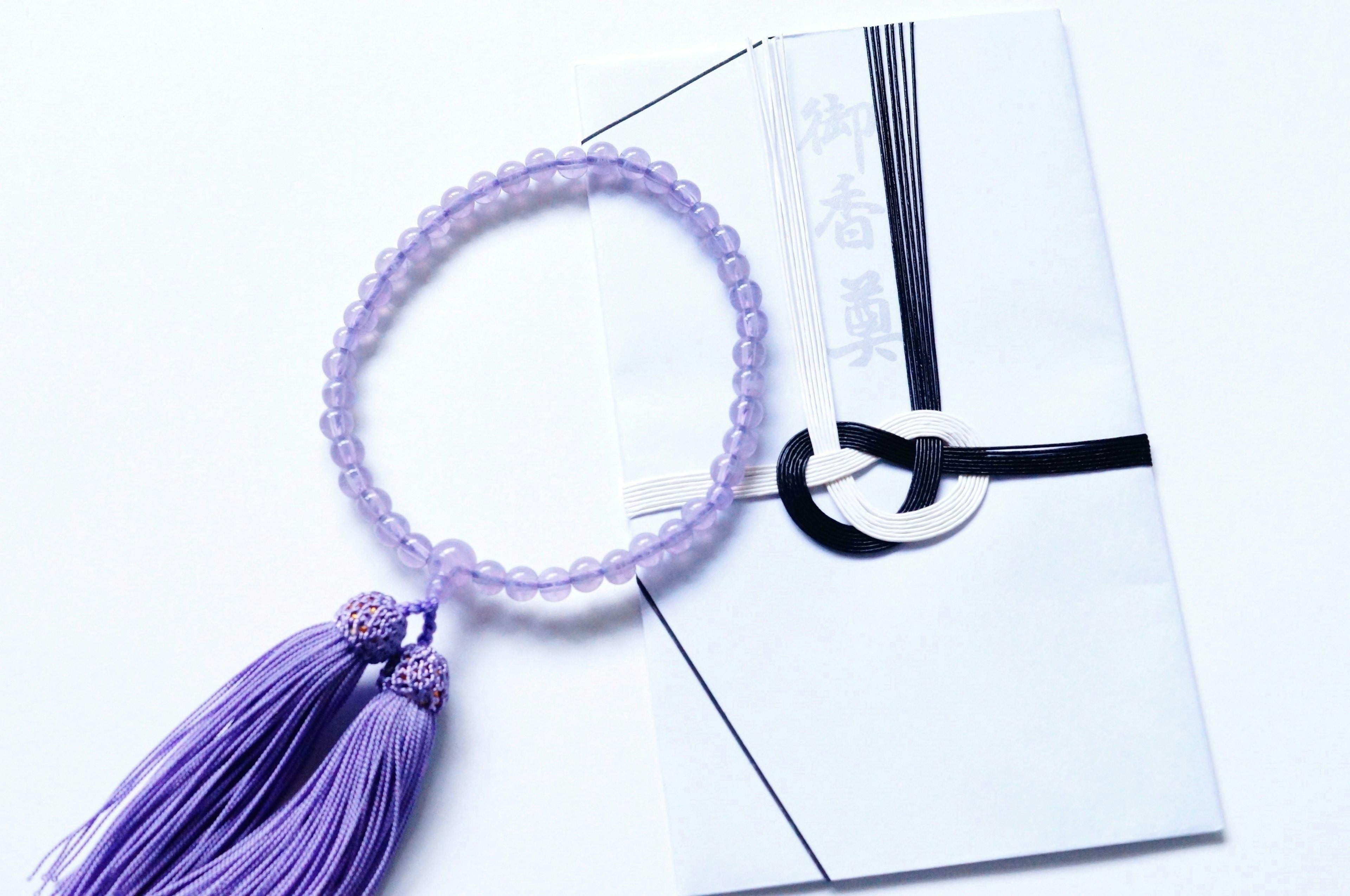 Bracelet à frange violet à côté d'une enveloppe blanche