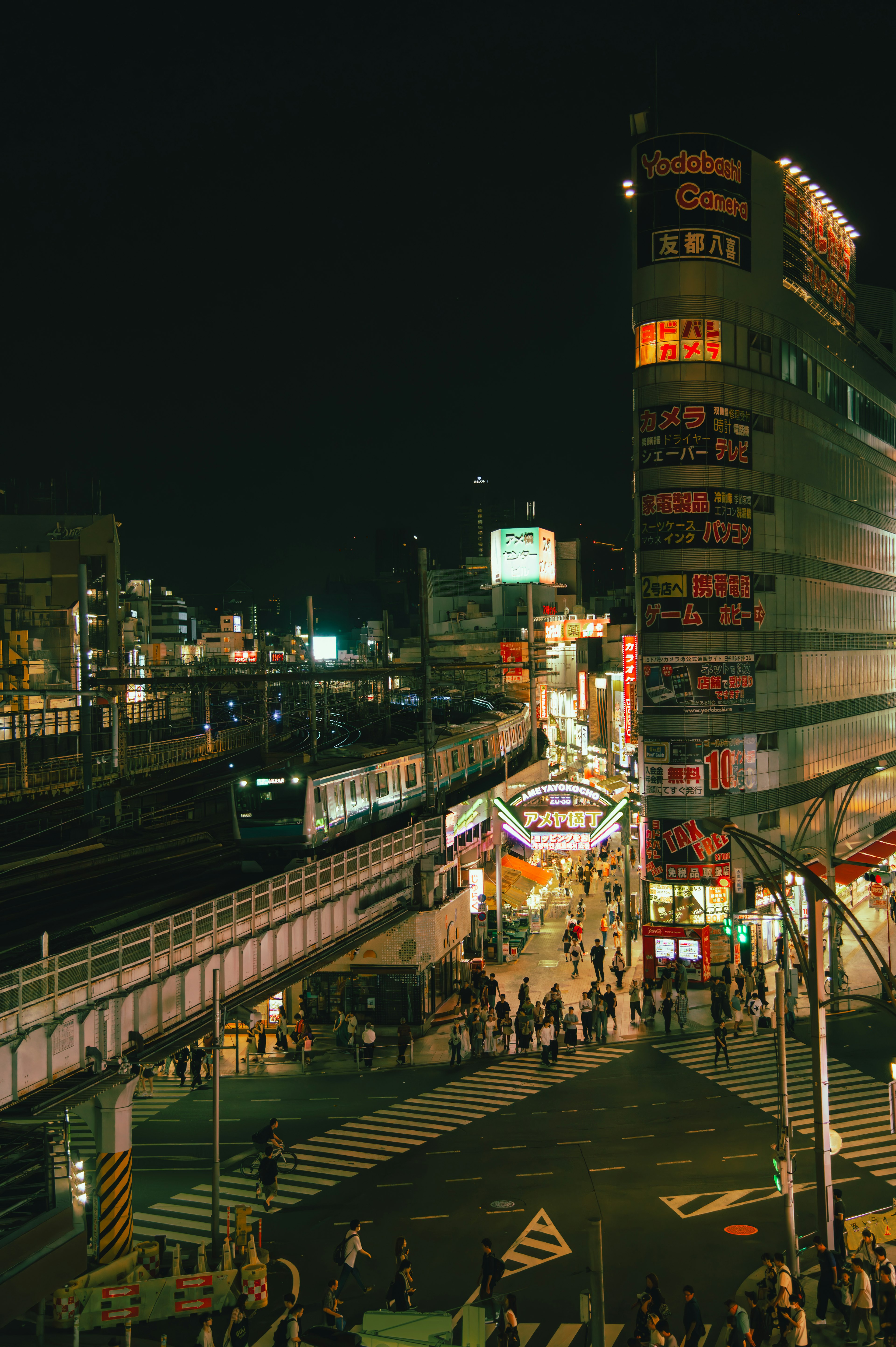 ทิวทัศน์เมืองที่มีชีวิตชีวาในตอนกลางคืนที่มีถนนที่พลุกพล่านและรถไฟ