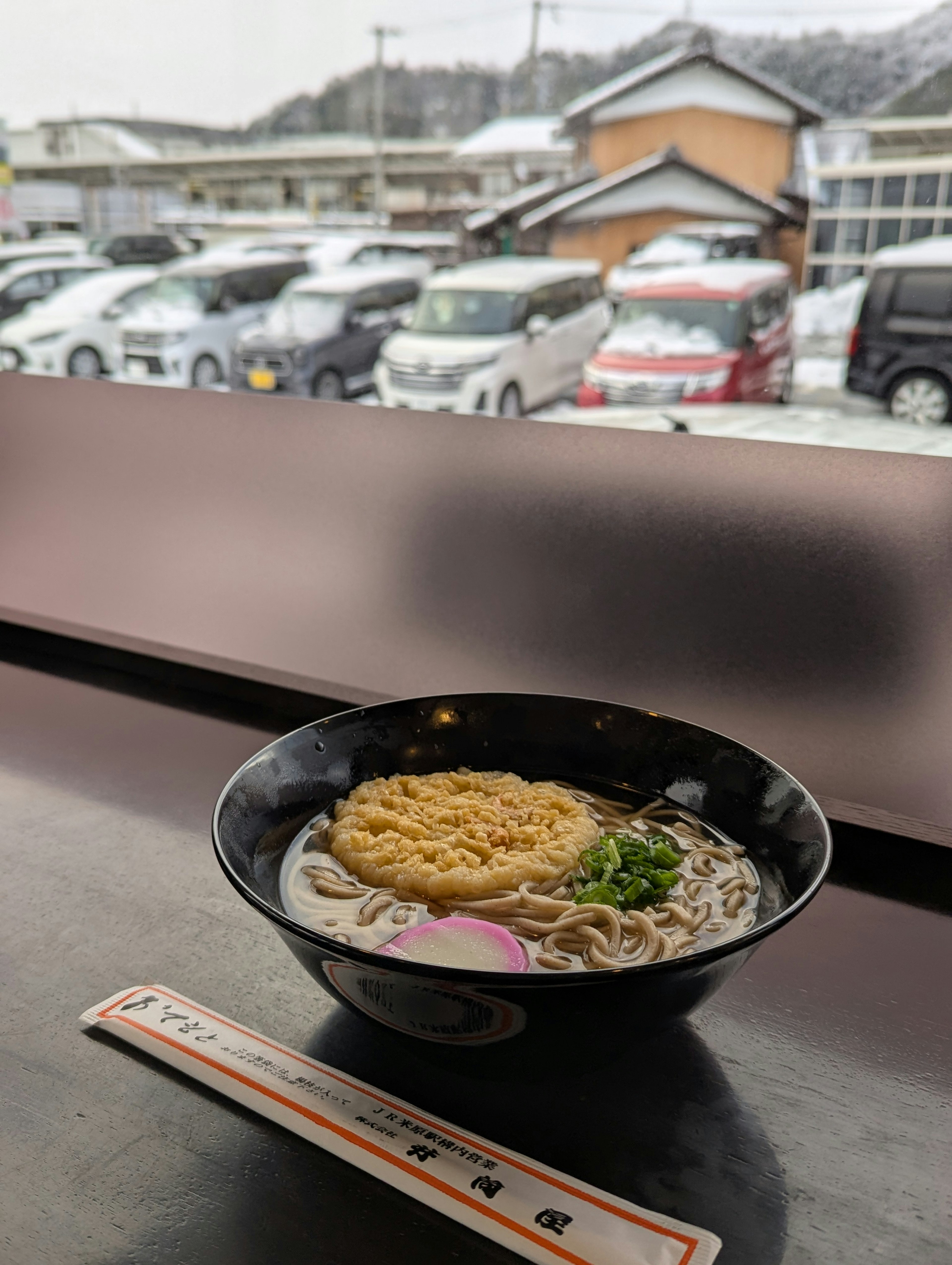 Un bol de ramen sur une table avec un paysage enneigé à l'extérieur