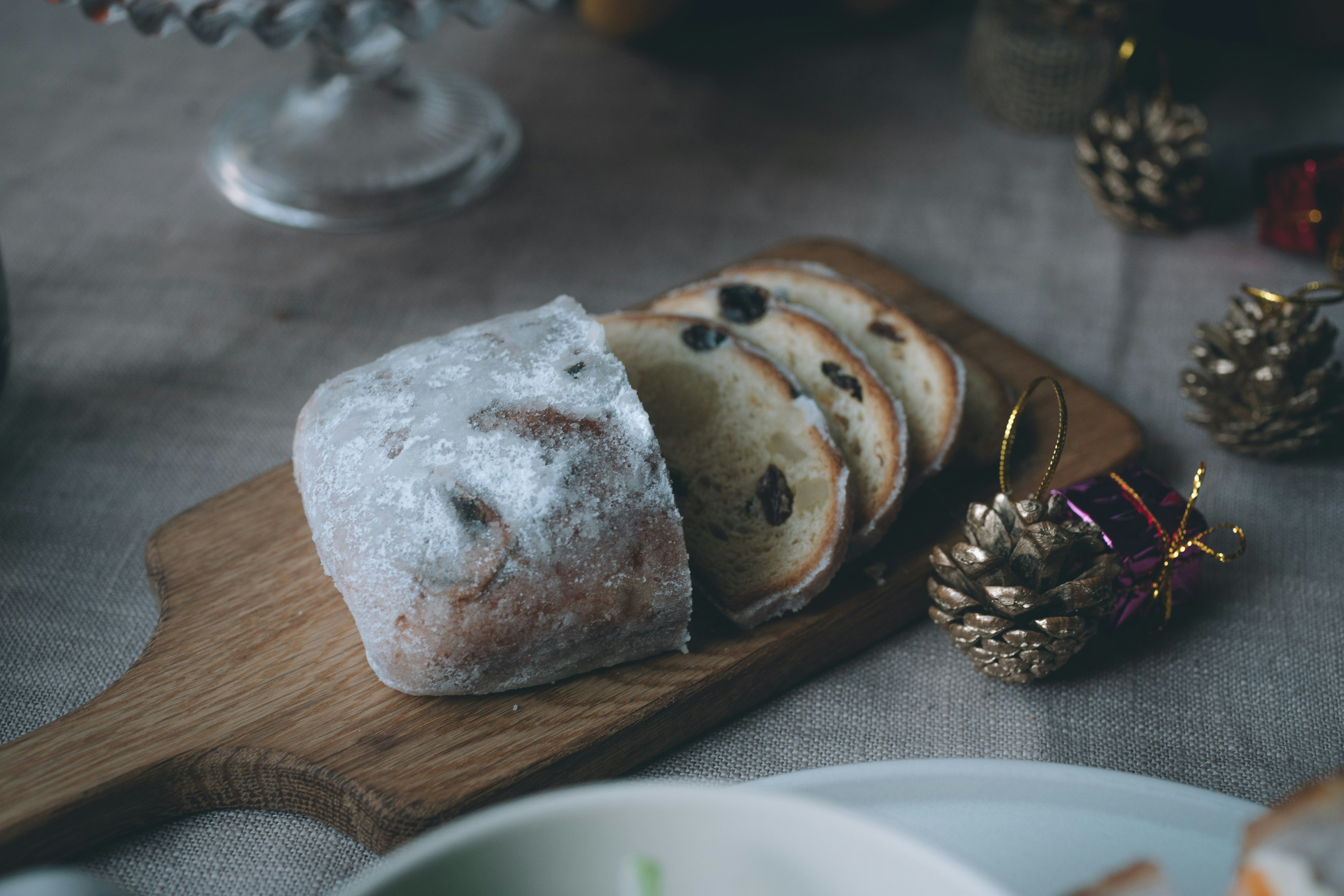 In Scheiben geschnittenes Weihnachtsbrot auf einem Holzbrett mit dekorativen Gegenständen