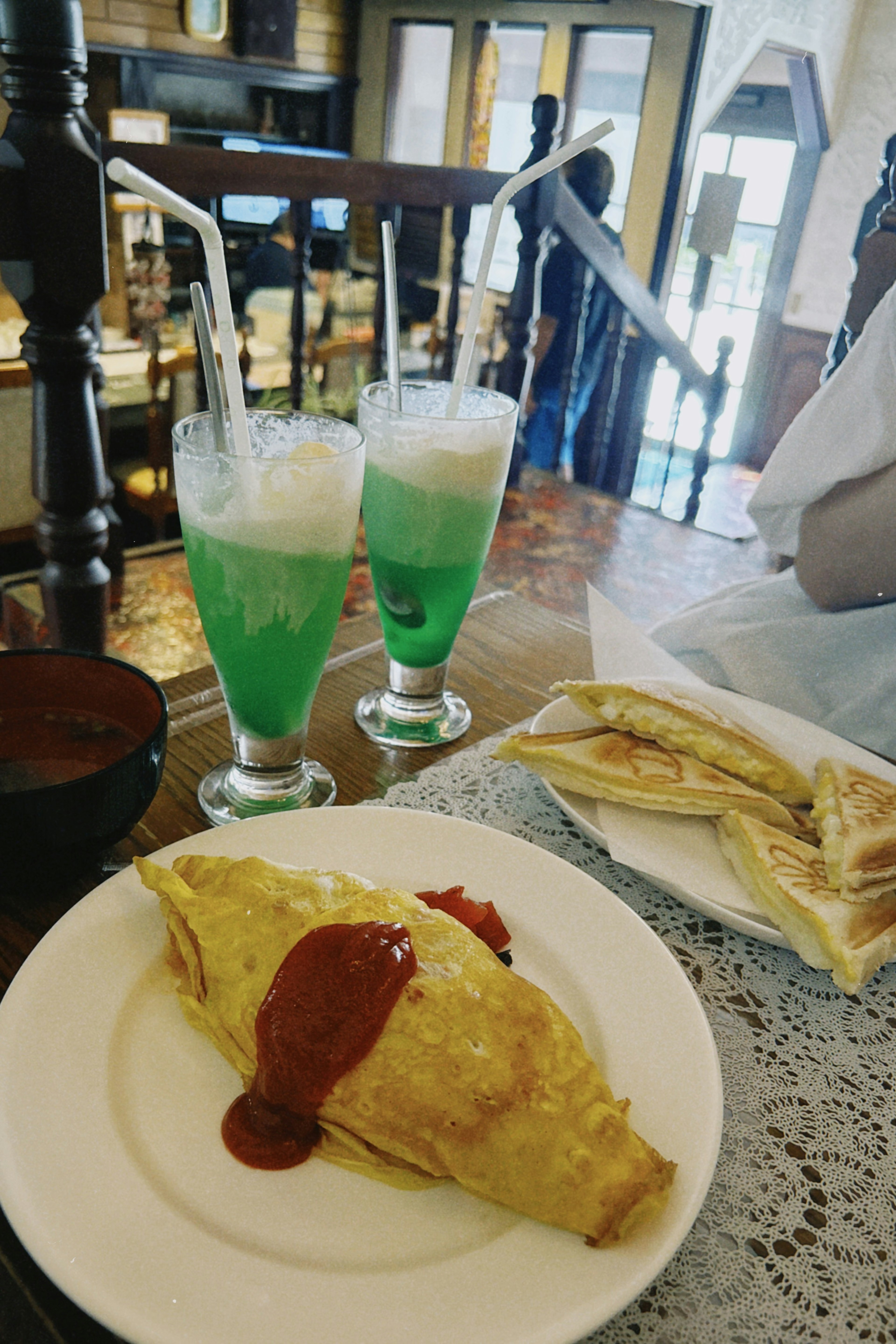 Table setting with green drinks and omelet topped with ketchup