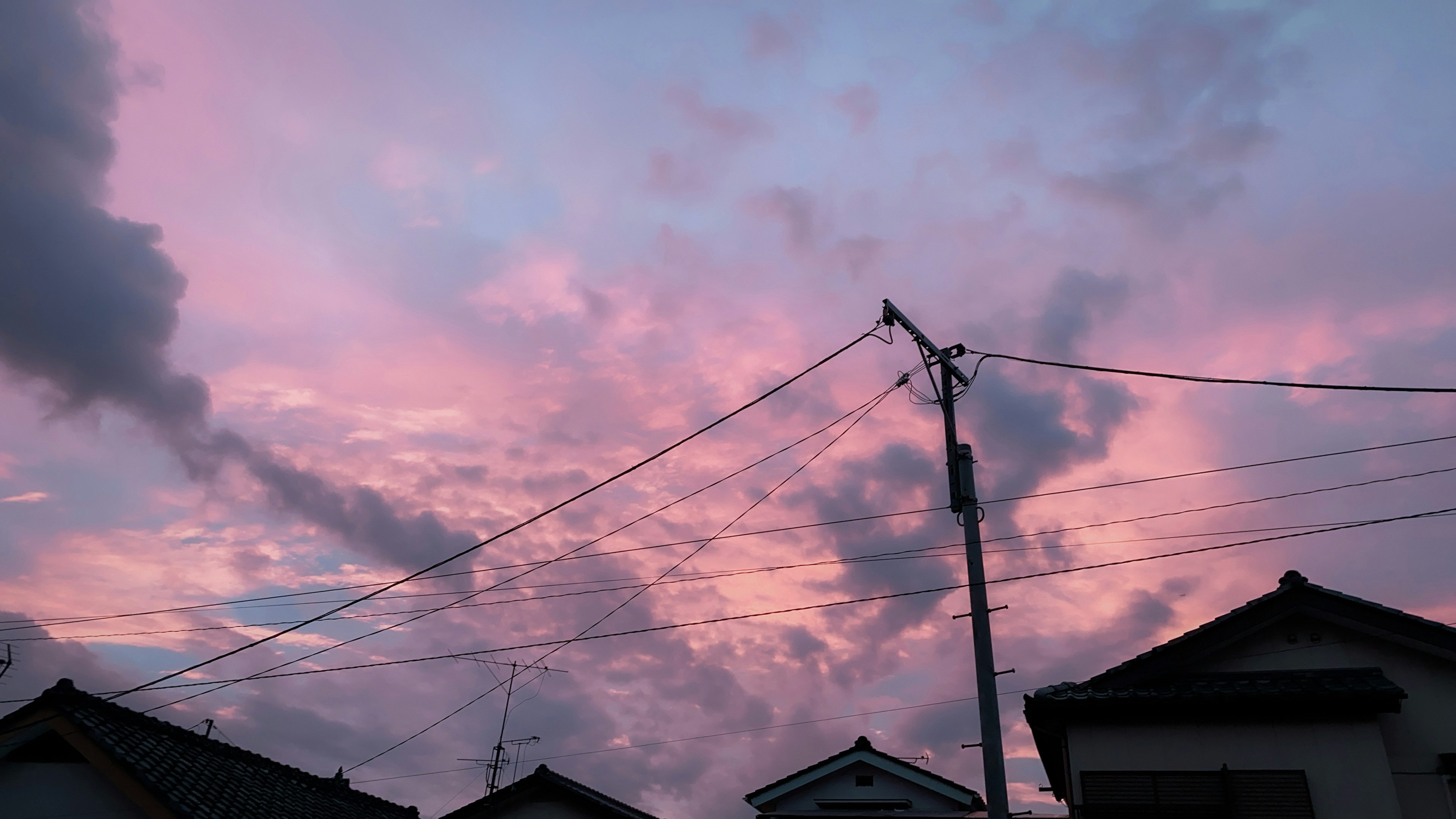 ท้องฟ้ายามเย็นมีเมฆสีชมพูและสีม่วงและเสาไฟฟ้า