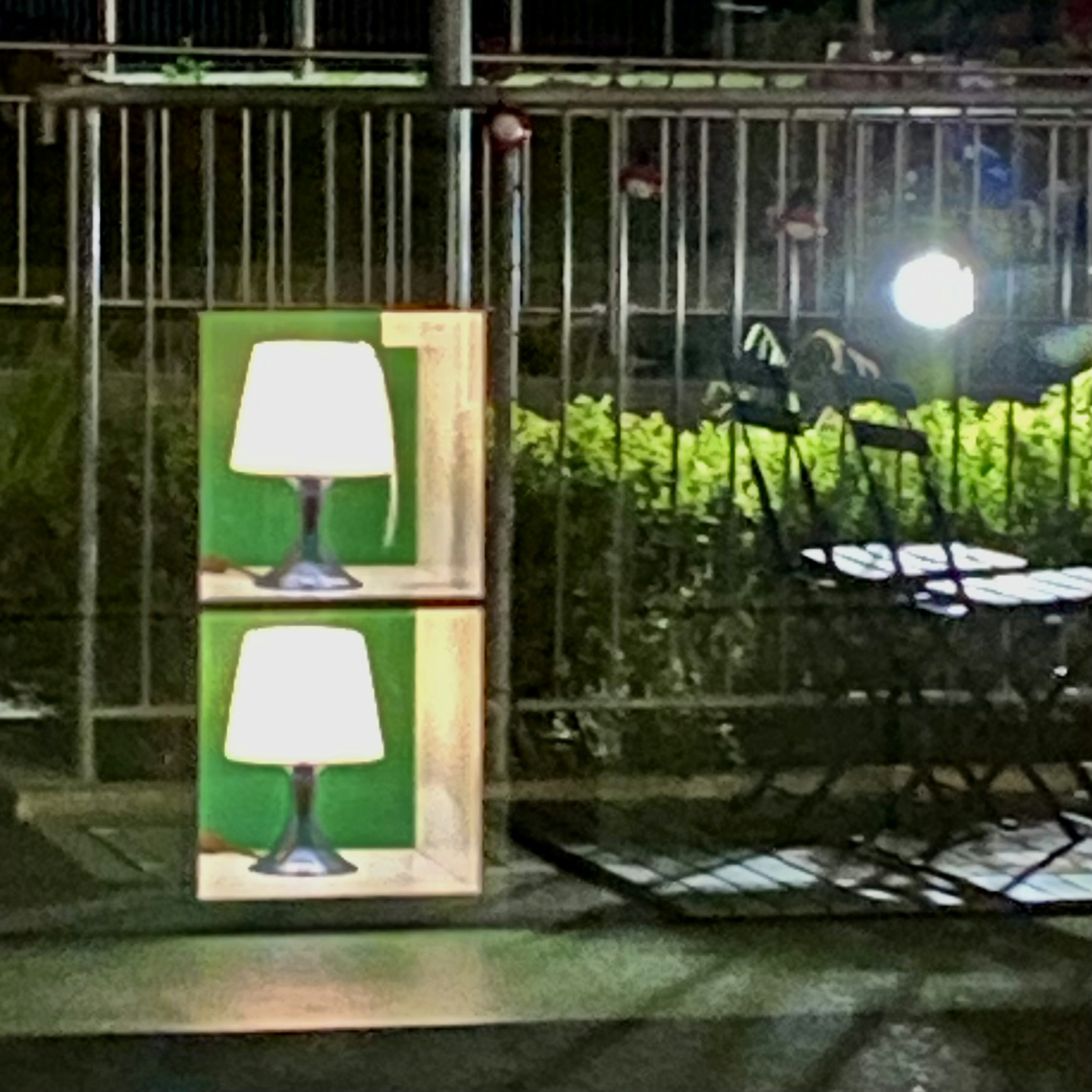 Wooden box with two lamps against a green background at night