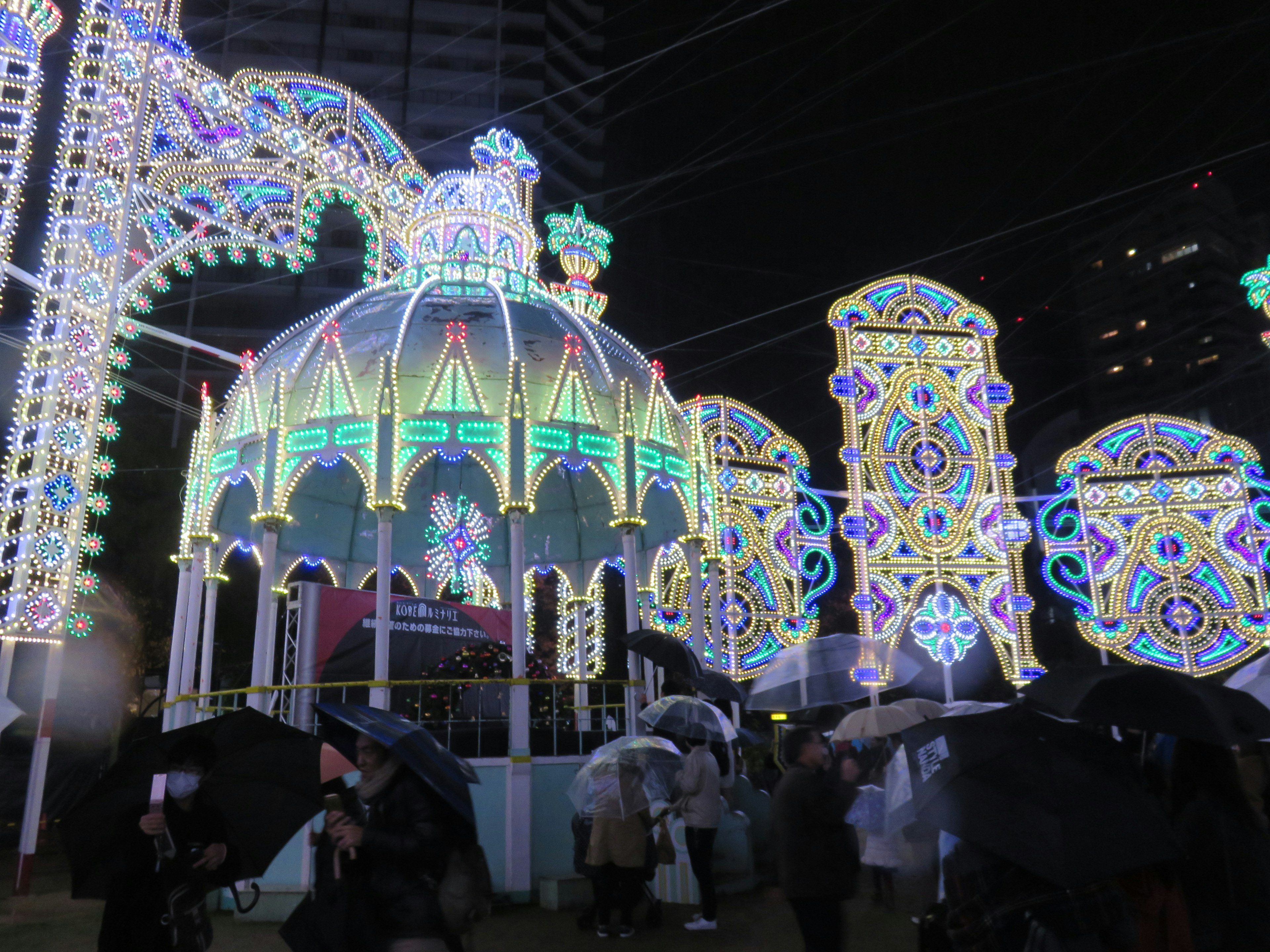 A beautifully illuminated dome structure surrounded by colorful lights and decorations in a nighttime setting