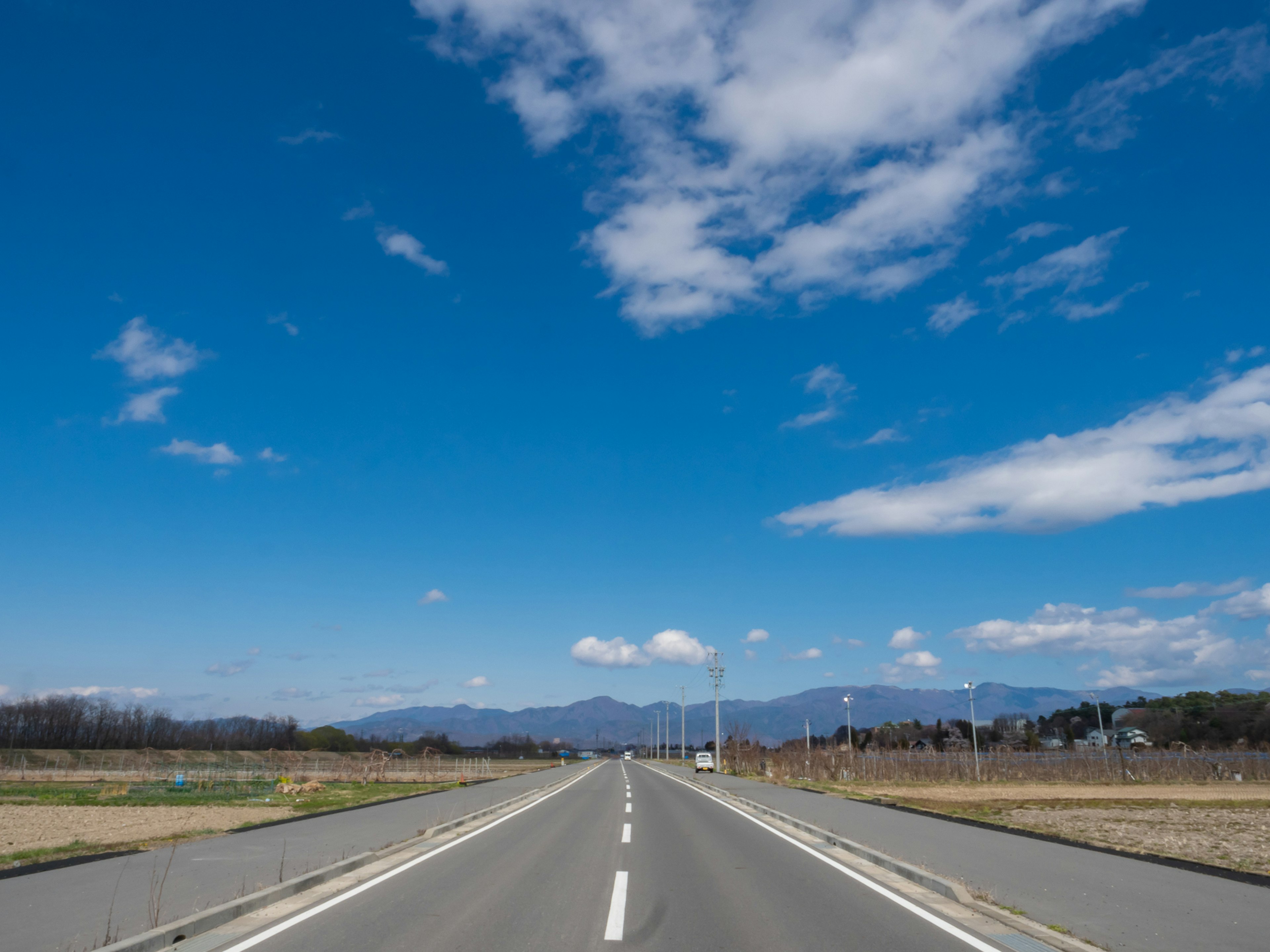 Une vue pittoresque d'une route sous un ciel bleu avec des nuages blancs