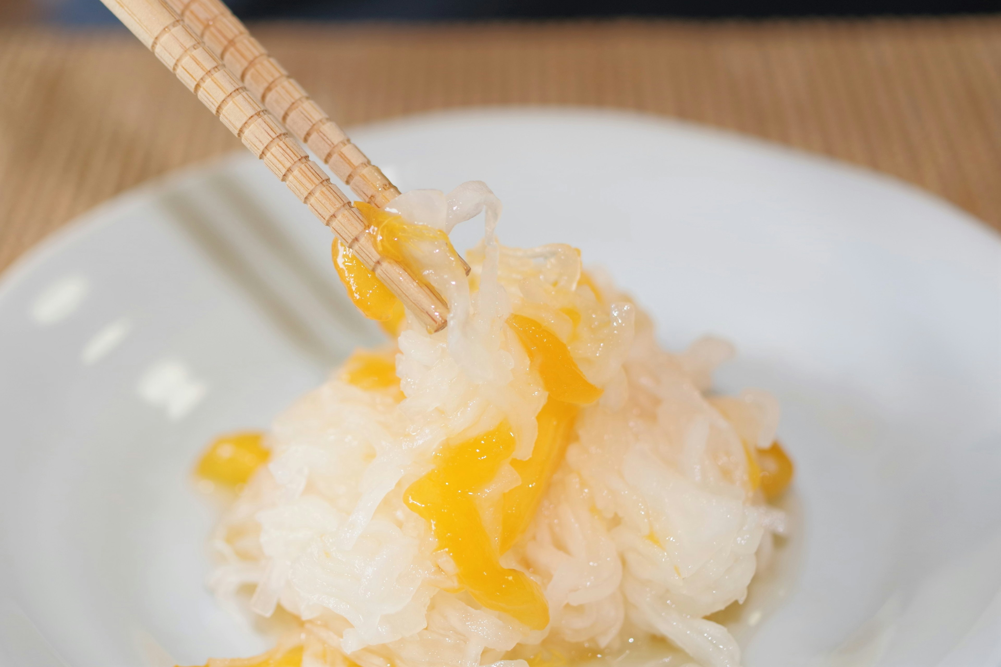 Ein Stück süßes Dessert mit Essstäbchen von einem weißen Teller gehoben